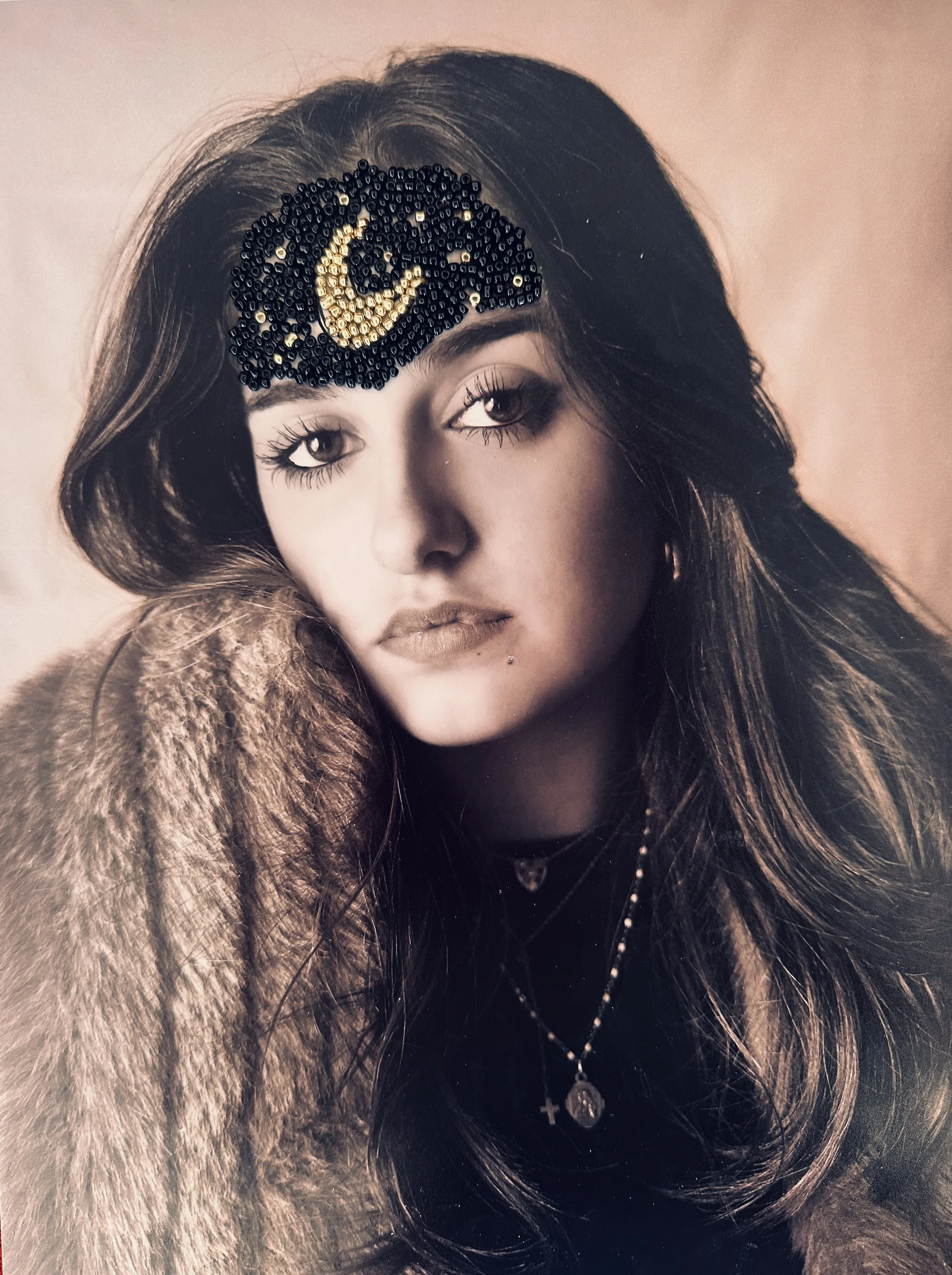 Portrait d'une jeune femme avec de longs cheveux bruns, portant un bijou  en perles pourvues d'un symbole de la lune. Elle porte également un manteau en fourrure et des colliers avec des pendentifs. art thérapie Lyon