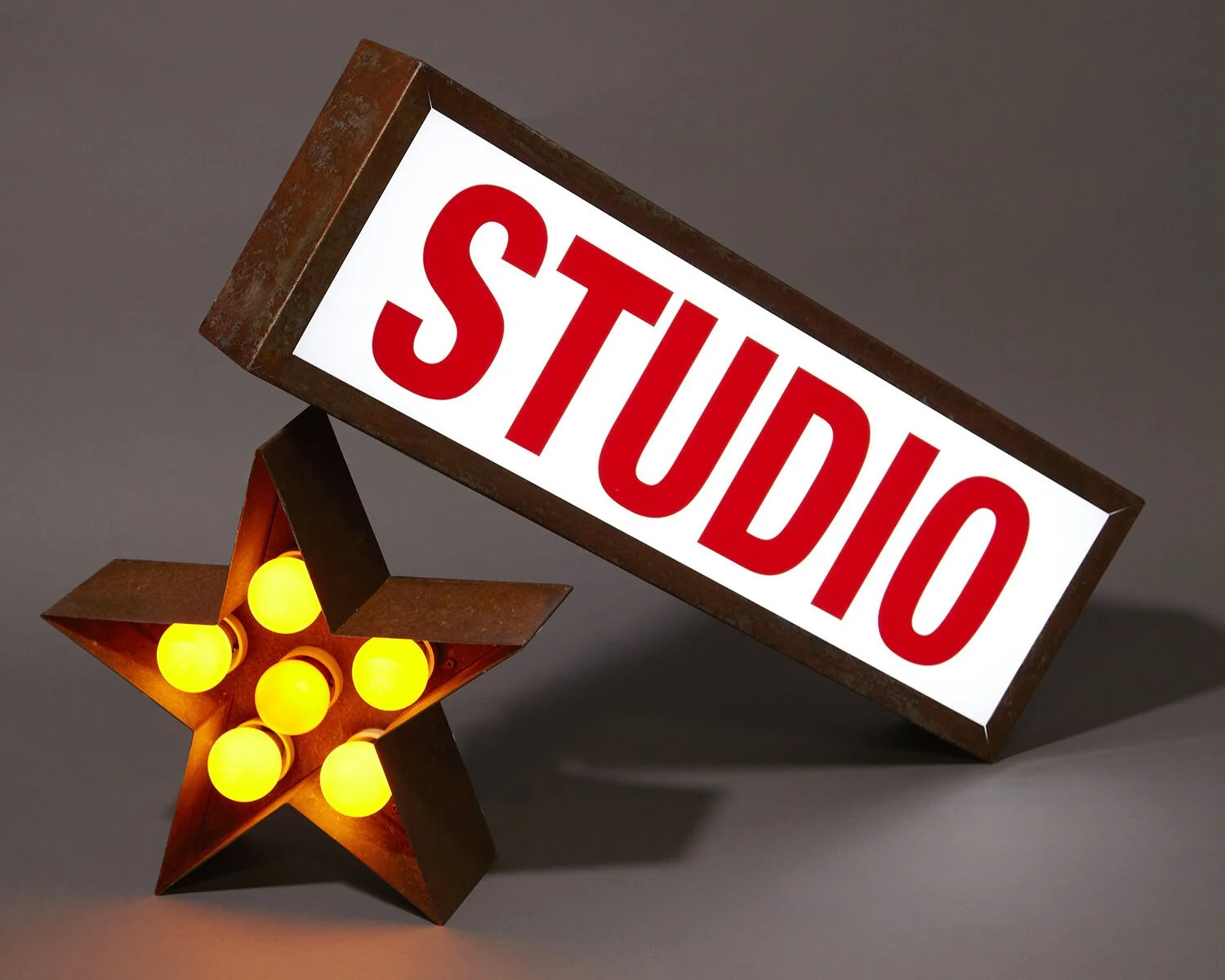 A illuminated sign with the word 'STOP' in red block letters on a white background, alongside a star-shaped lamp with yellow light bulbs.