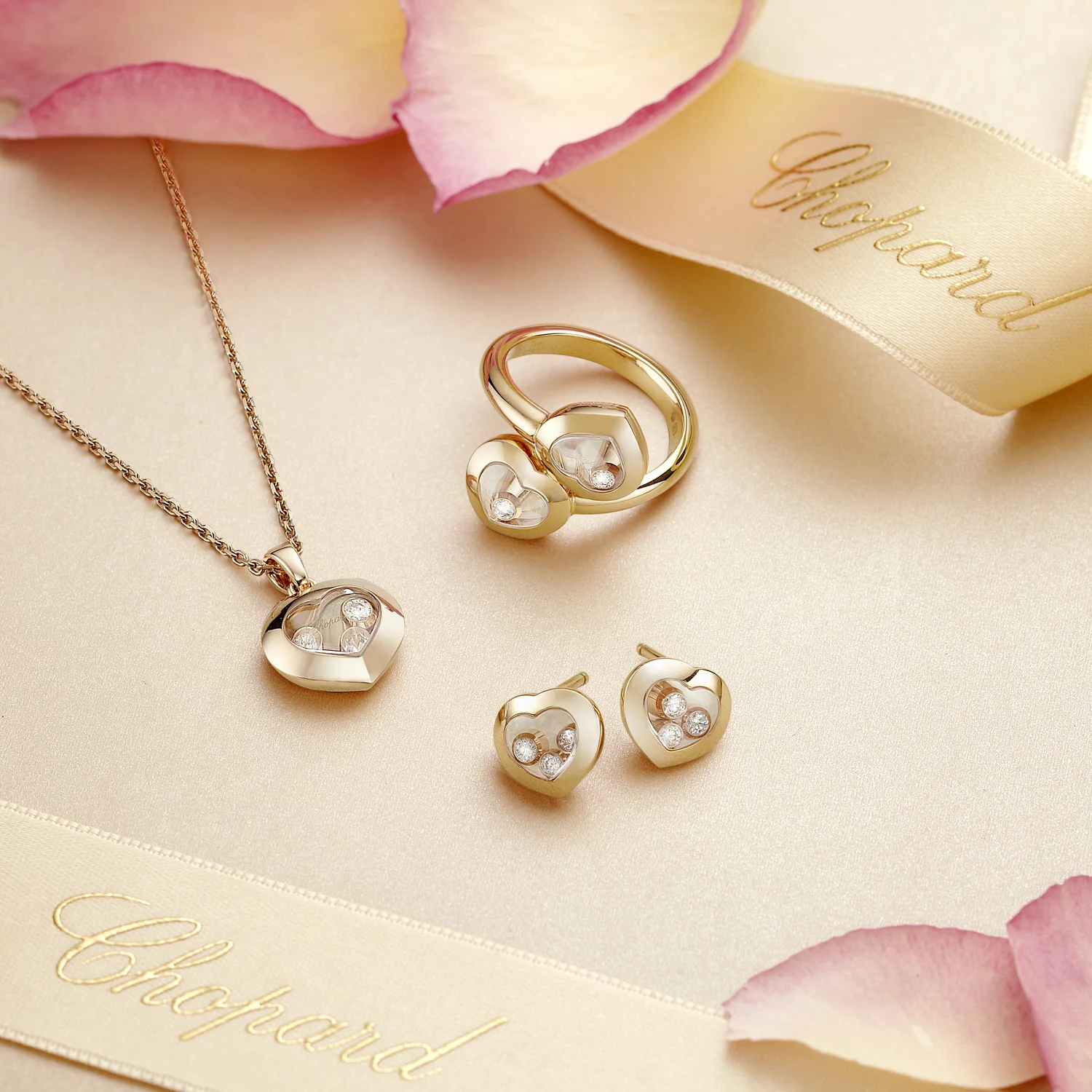 set of three gold pieces of jewellery surrounded by ribbon and flower petals, creative jewellery photography