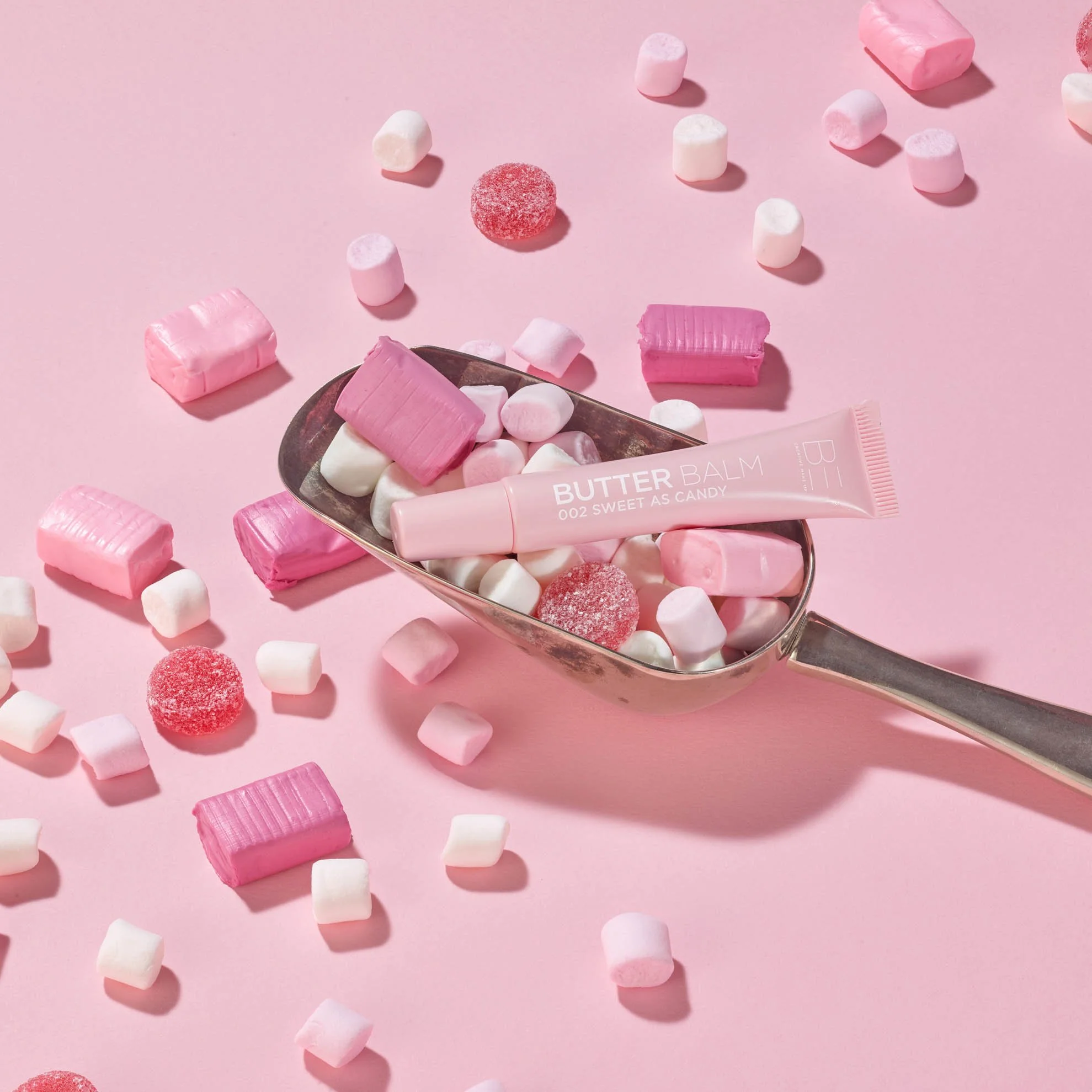 pink butterball cosmetic product surrounded by sweets and candy