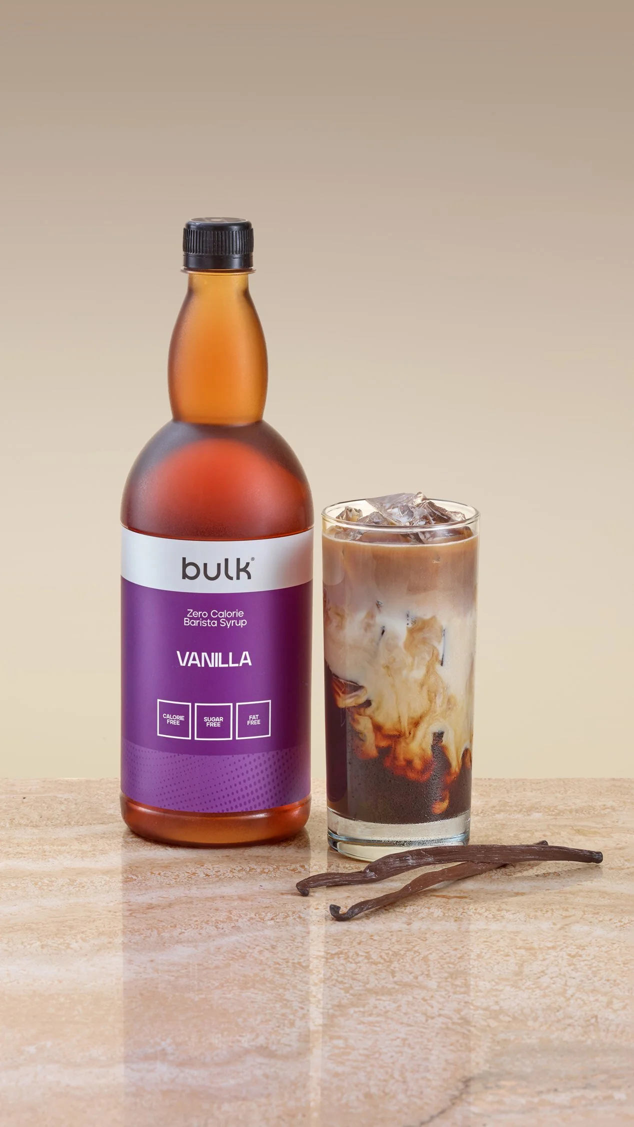 Bulk syrup product photographed with natural vanilla pods on marble table