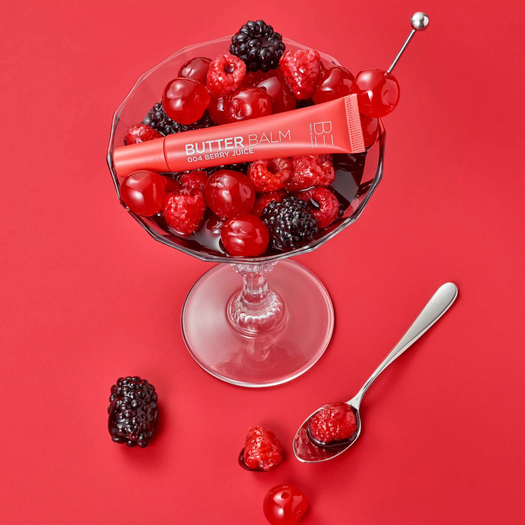 berries in glass on red background with cosmetic product in the middle