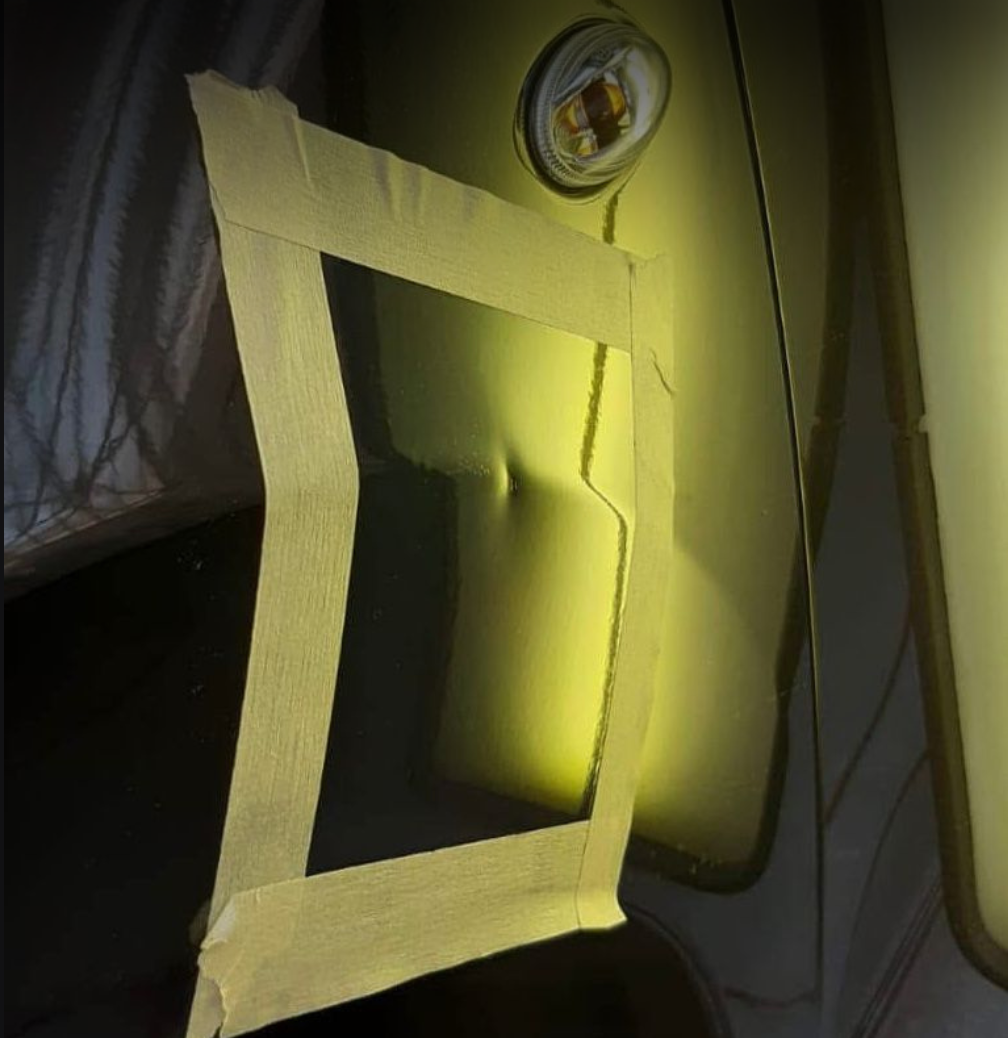 Car with a headlight taped off with masking tape and a glowing yellow light.