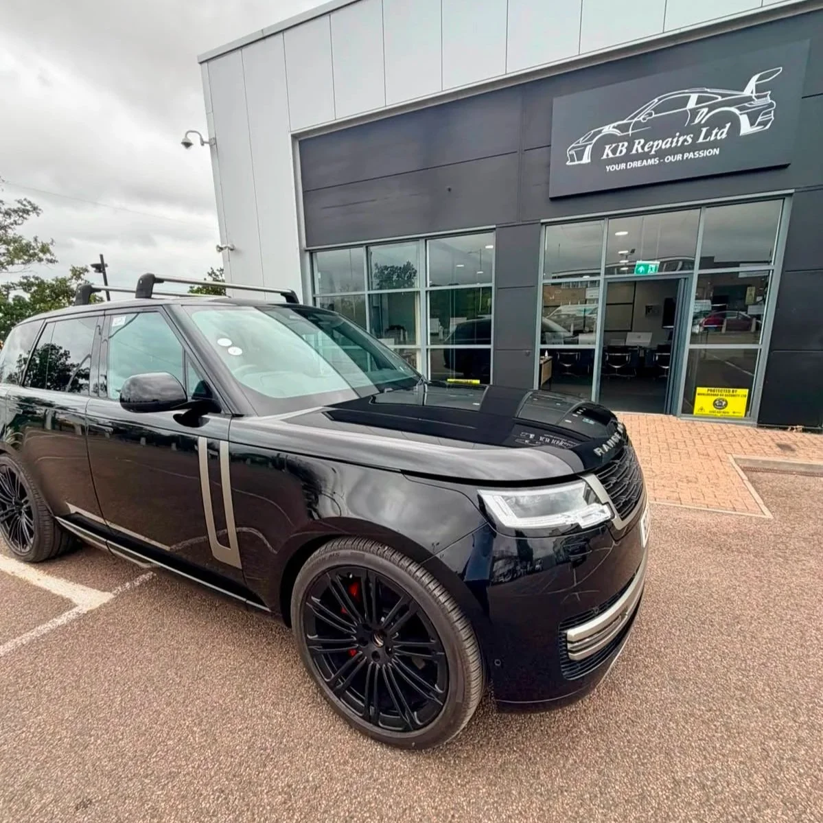 Black Range Rover parked outside KB Repairs Ltd automotive repair shop with a modern exterior and large windows.