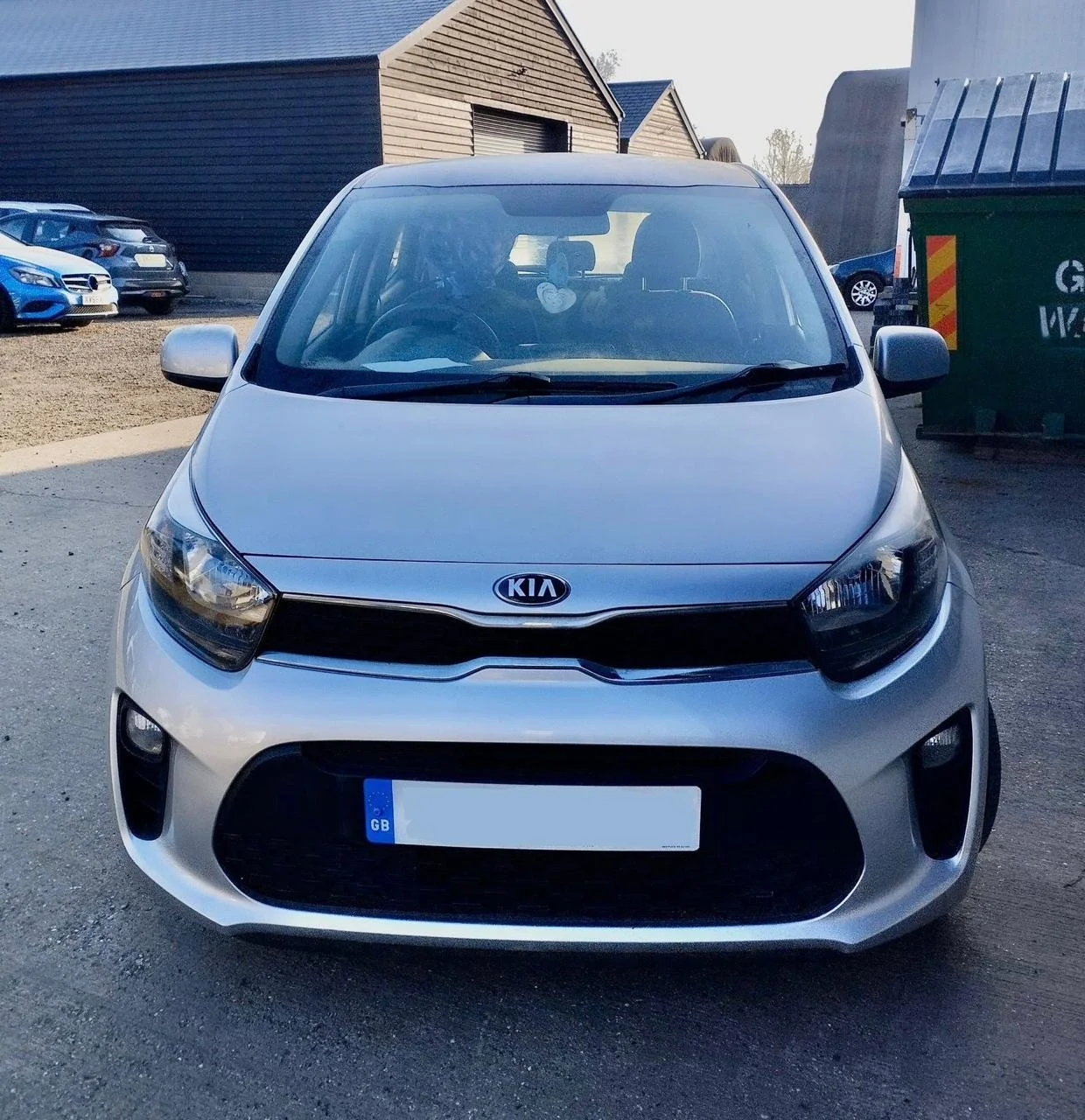Front view of a silver Kia hatchback car parked outdoors.