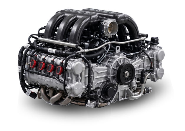 A high-performance Porsche engine with black and silver components, including intake manifolds, ignition coils, and various pipes and hoses.