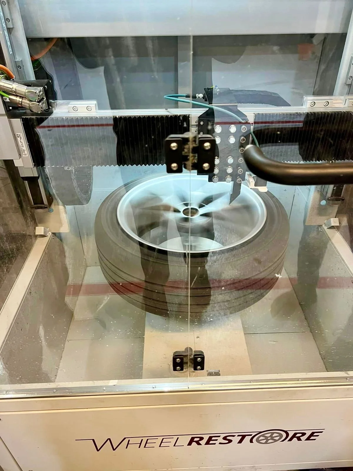 A tire is inside a specialized machine for wheel balancing, with the machine spinning the tire.