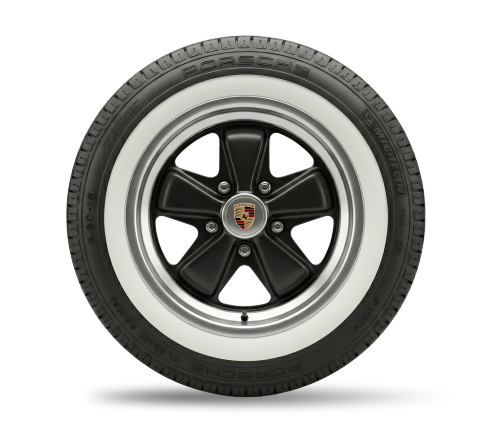 Close-up of a vehicle wheel with a black and silver rim, featuring a Porsche emblem at the center.