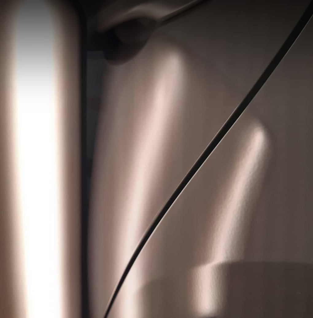 Close-up of a metallic, curved surface with smooth, shiny texture and subtle reflections.