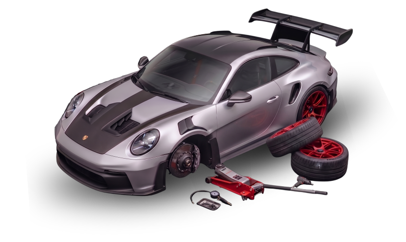 A silver Porsche race car with black accents and a large rear wing, shown with its wheels removed, tires and red rims, and various tools around it for maintenance or repair.