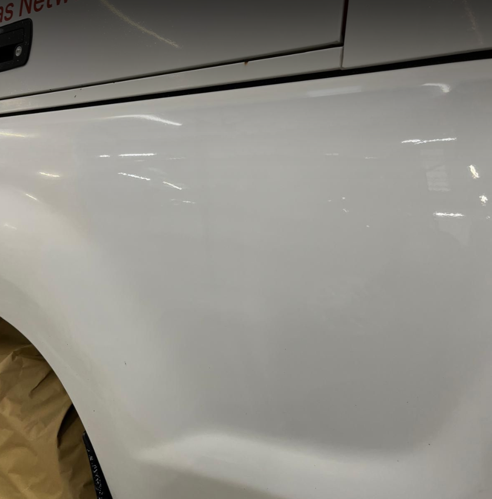 Close-up of a white car's body with minor scratches and a dent