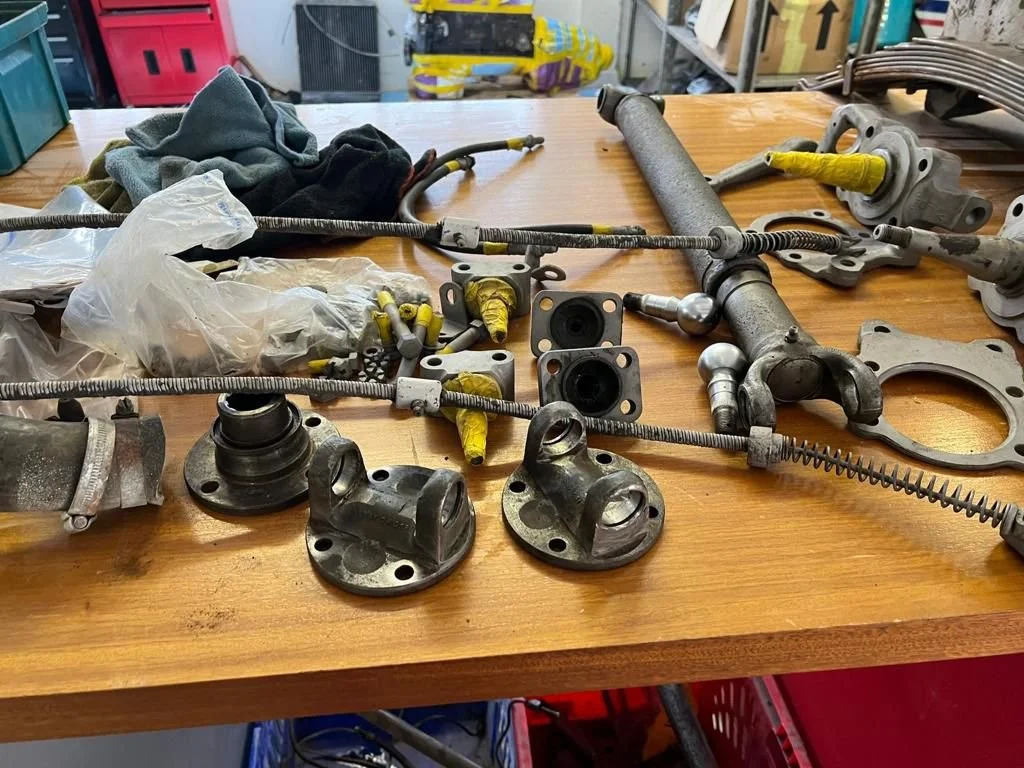 Disassembled automotive parts and tools on a wooden workbench in a workshop.