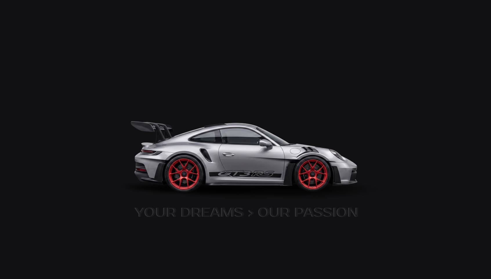 Silver Porsche 911 GT3 RS with red wheels and a large rear wing on a black background, with the slogan "Your Dreams > Our Passion" beneath it.