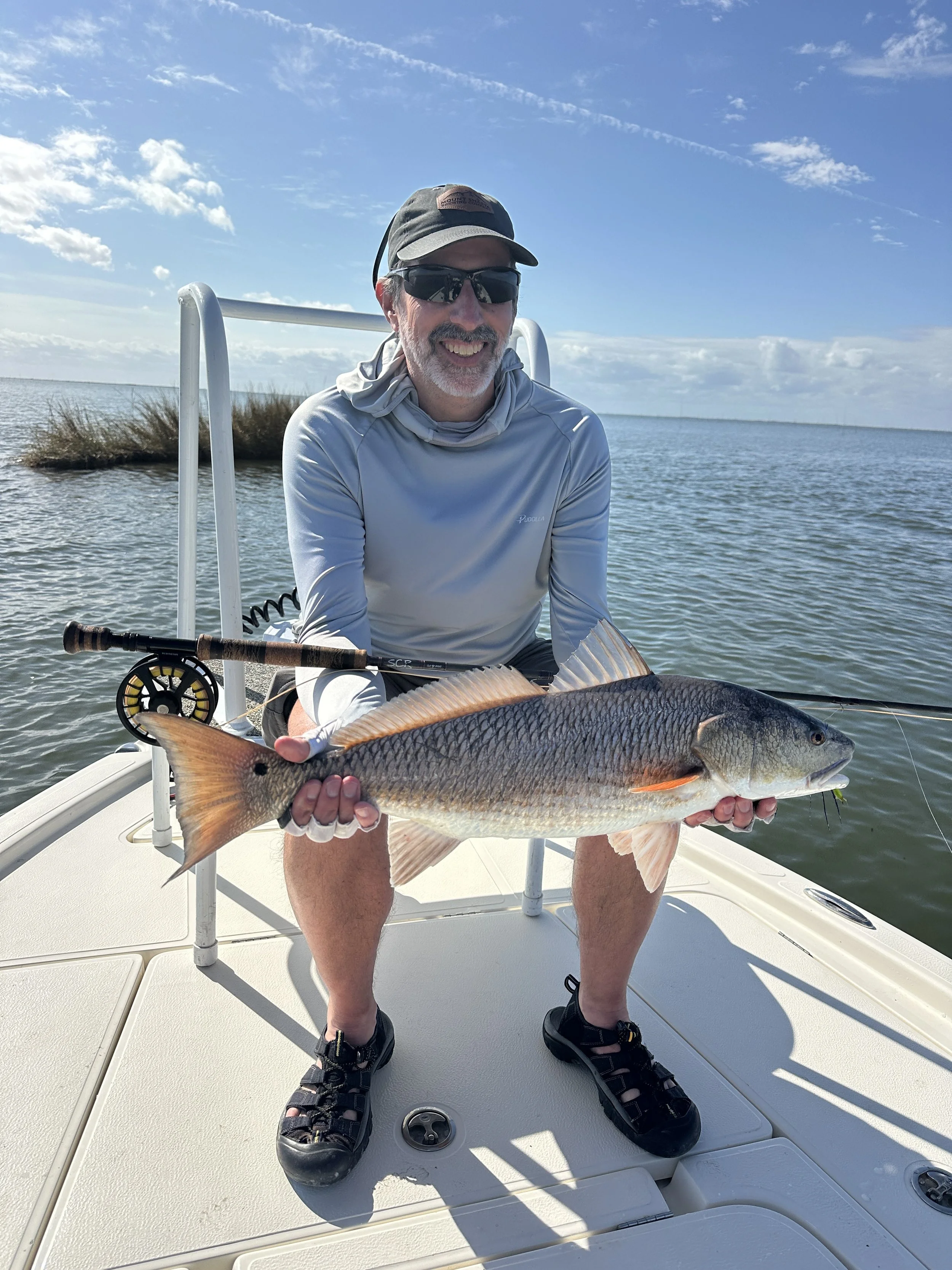 Angler smiling while holding first redfish ever caught on fly.