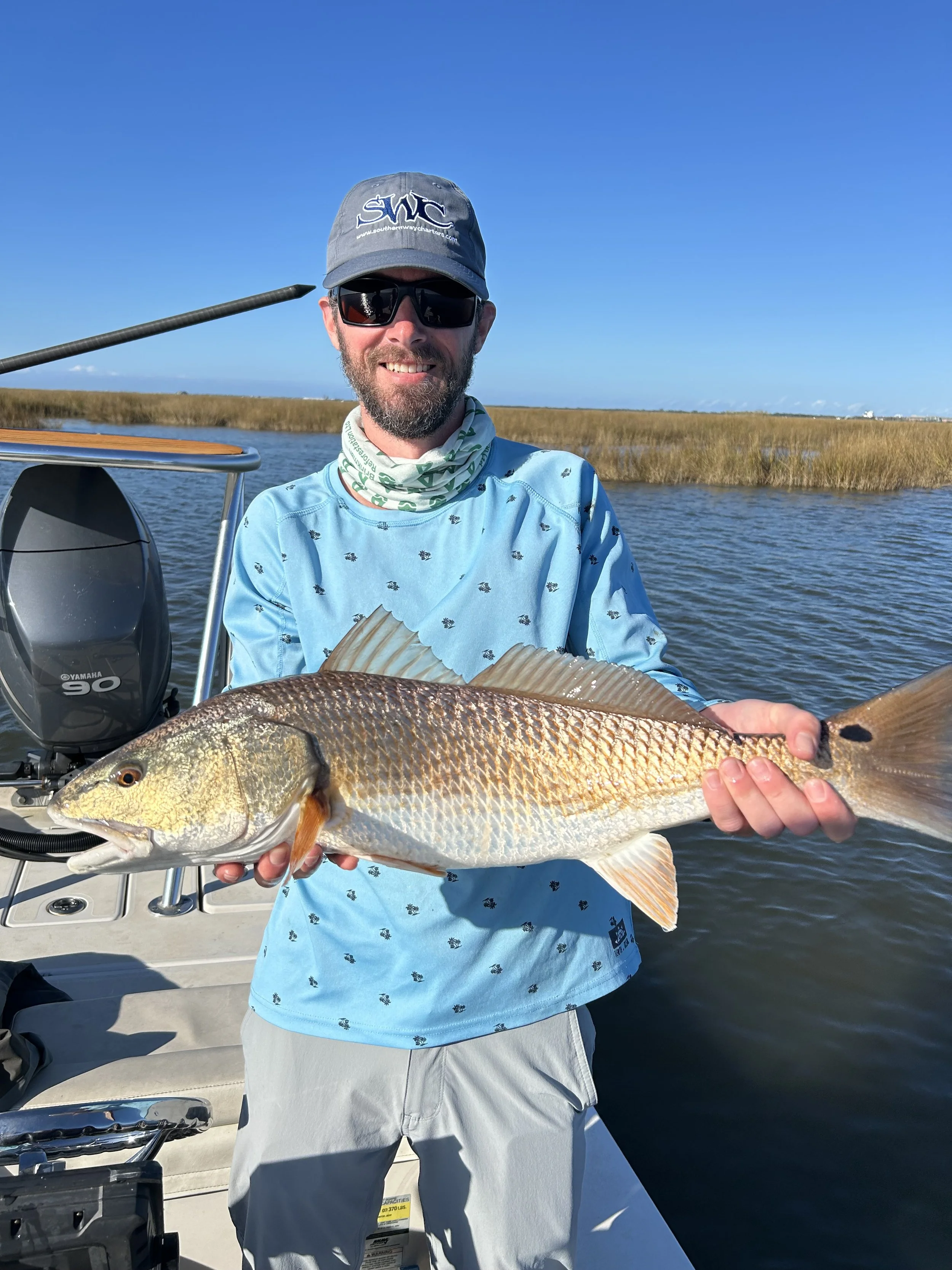Client smiling with a slot redfish caught during a Louisiana guided fishing trip.