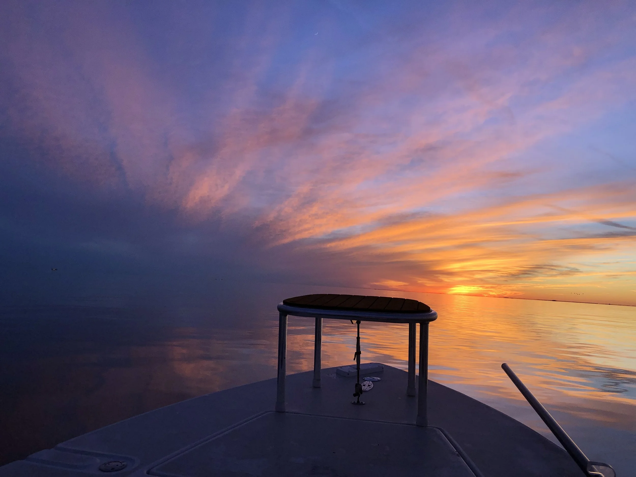 “Center console fishing boat running through the Louisiana marsh at sunset.”