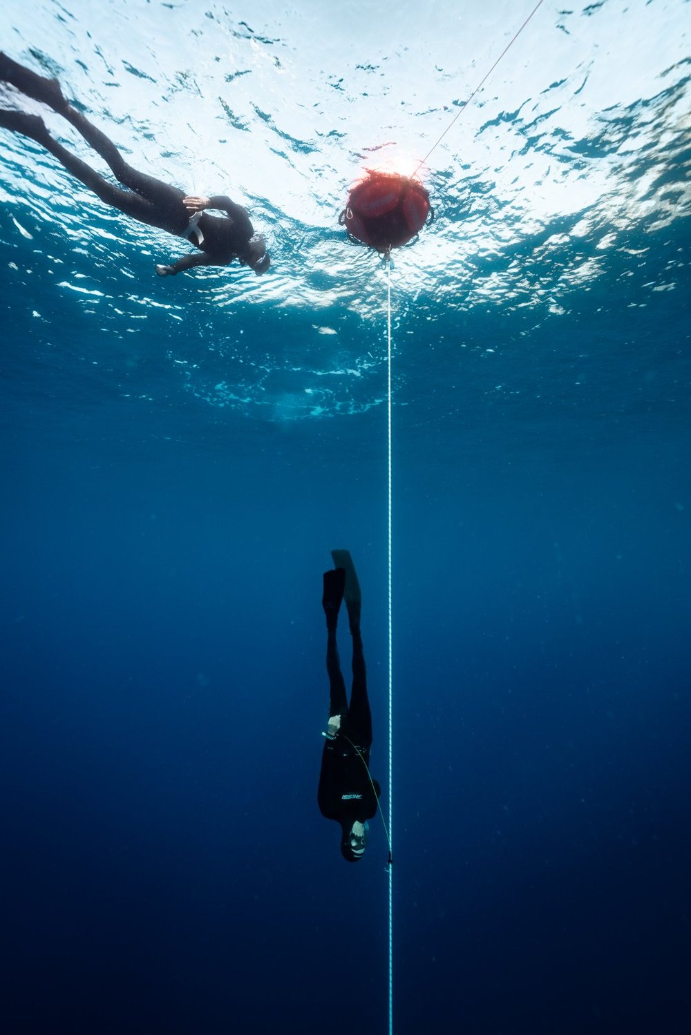 A freediver starting its dive in Constant Weight with the instructor doing surface safety