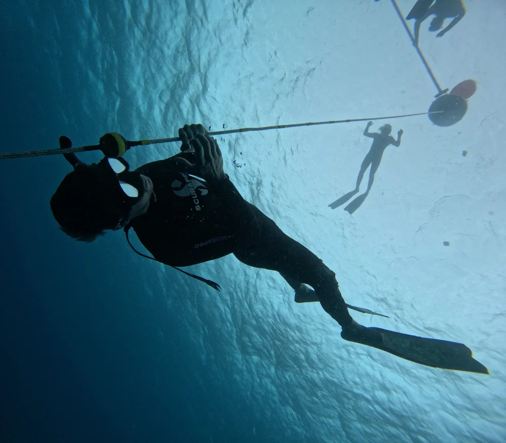 A student freediver in Tenerife reaching the stopper, watched by the instructor on the surface