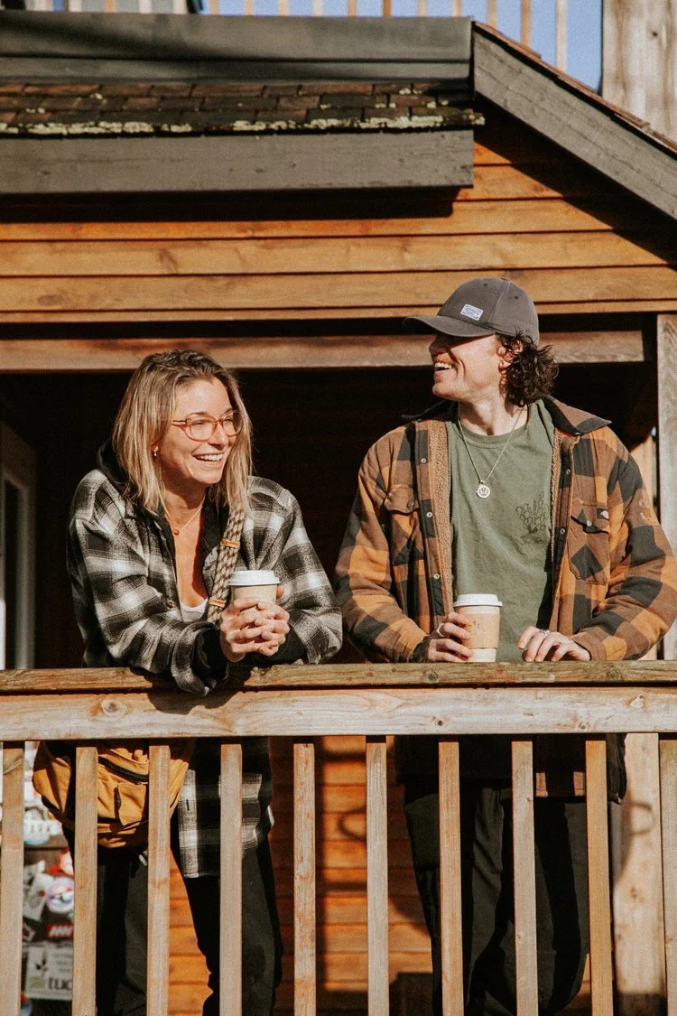 Two men with tattoos raising their hands in a forested outdoor setting.