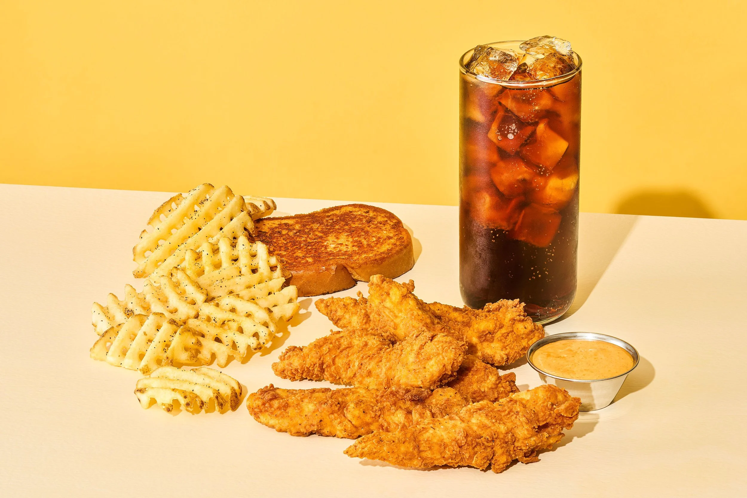 Five crispy chicken tenders served with fries, garlic Parmesan toast, a Coca-Cola, and sweet sriracha sauce