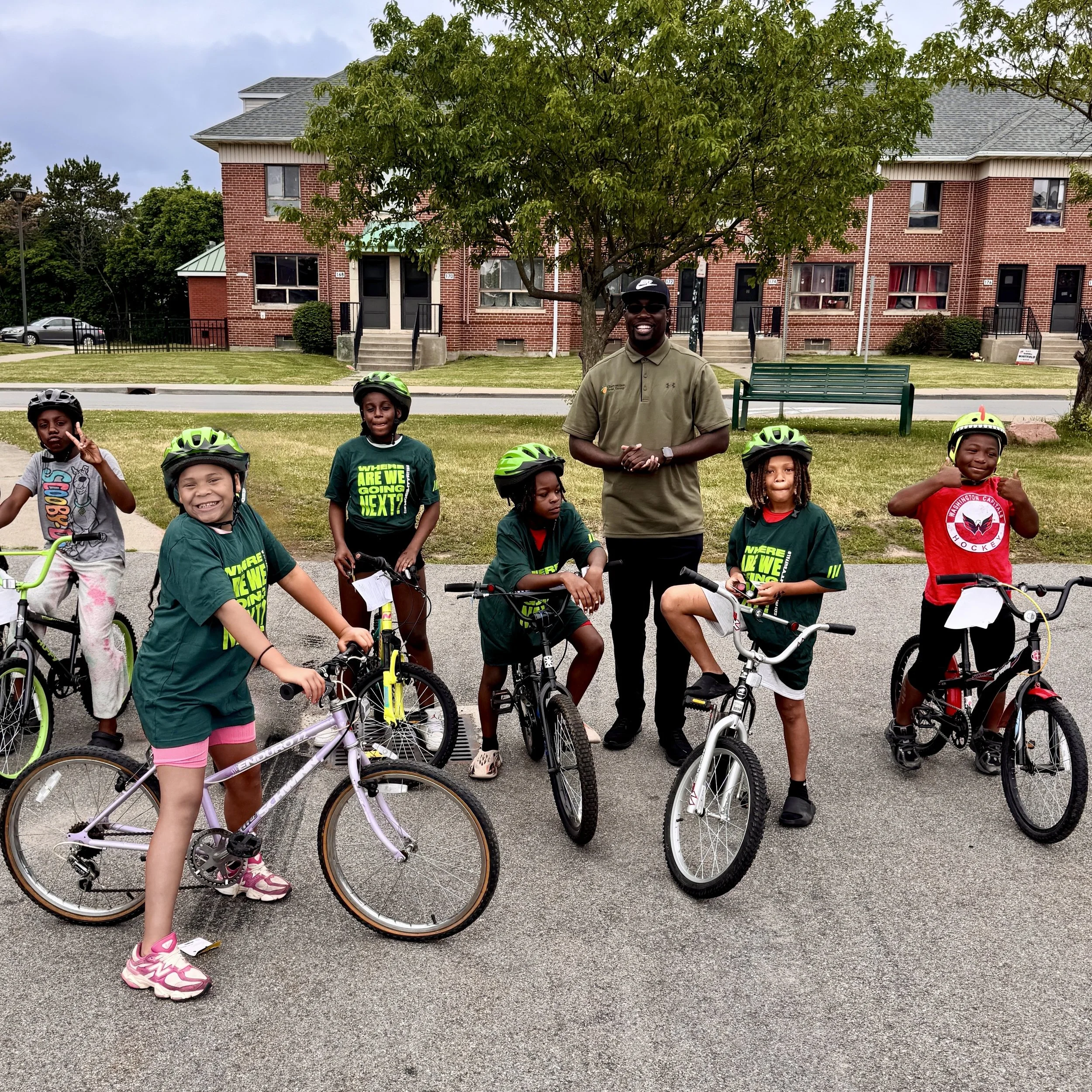 Build-A-Bike 6/26/25 — A group of kids standing outside on bikes wearing Clean Mobility Buffalo tee shirts 