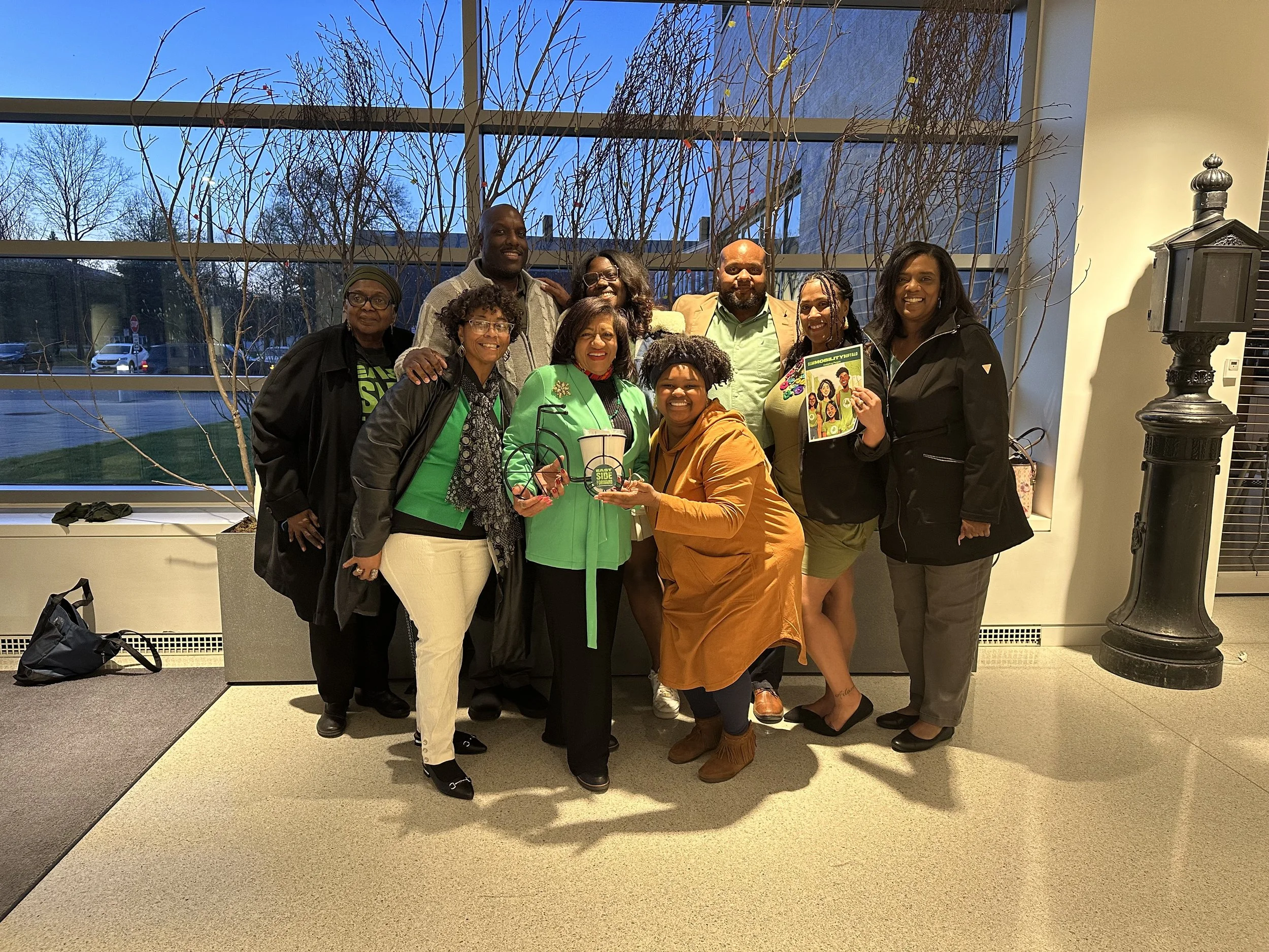 Neighborhood Leadership Group at Ride Reels — An image of a group of people holding a metal bike at the Burchfield Penney Art Center.