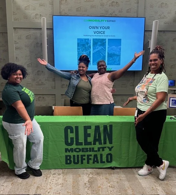 Own Your Voice Event 9/22/25 — An image of a group of people standing behind a table labeled "Clean Mobility Buffalo".