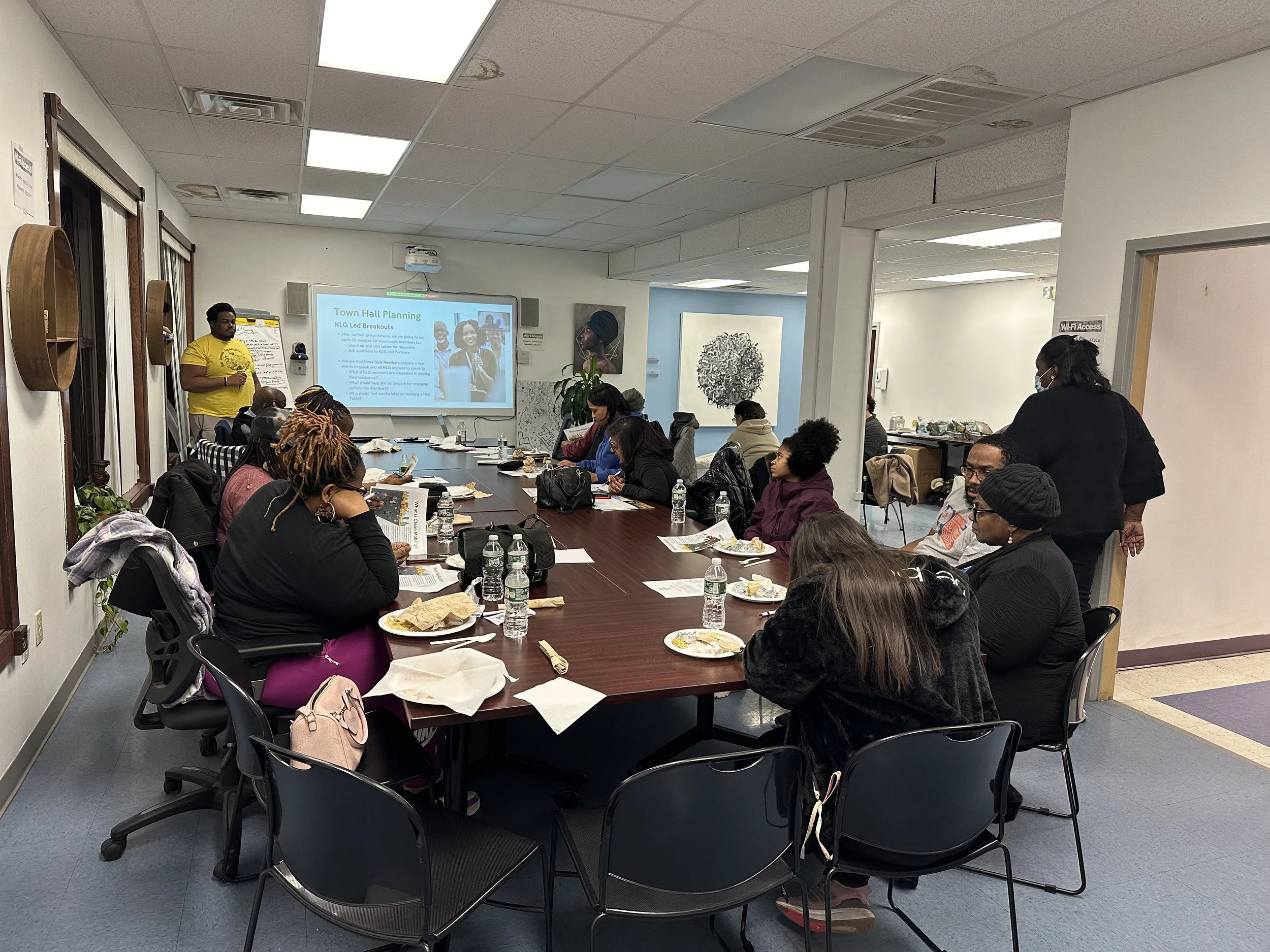 Neighborhood Leadership Group Meeting 1/31 — an image of a group of people surrounding a table and looking at a presentation screen.