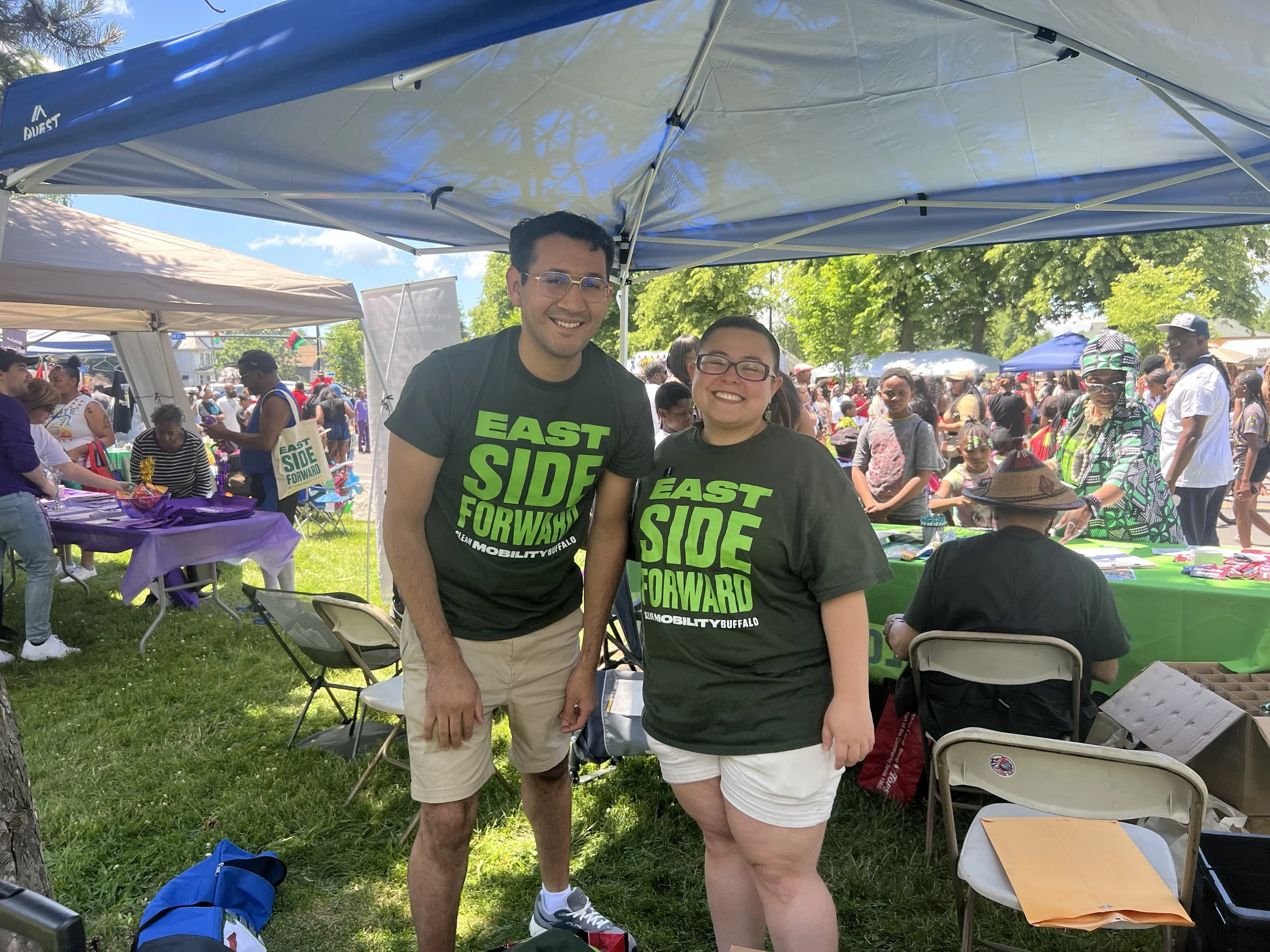 An image of two people smiling and wearing tee shirts labeled "East side Forward"