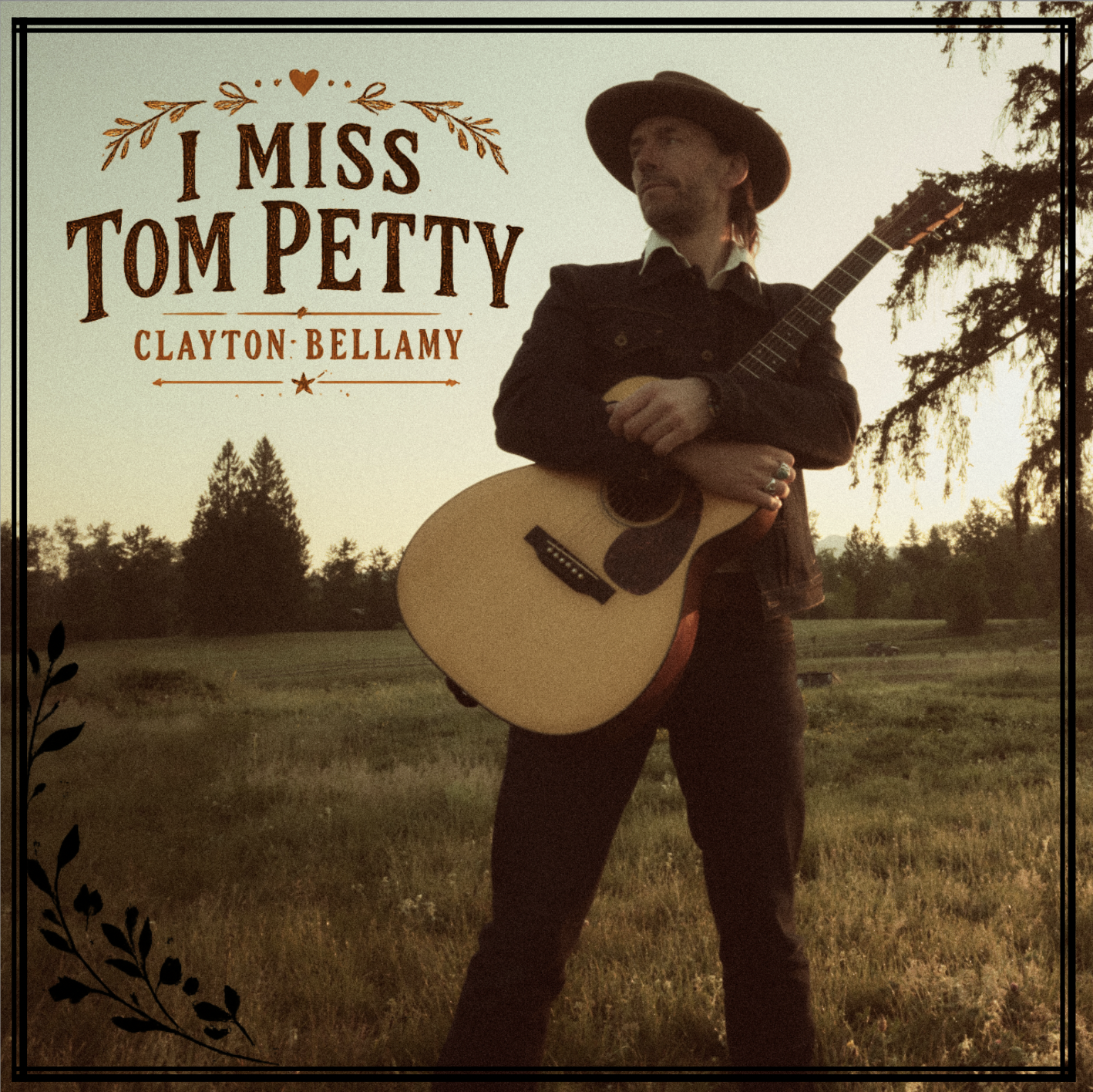 Man standing outdoors holding an acoustic guitar with trees and fields in the background at sunset, with the text "I Miss Tom Petty" and "Clayton Bellamy" and decorative elements in the upper left and lower left corners.