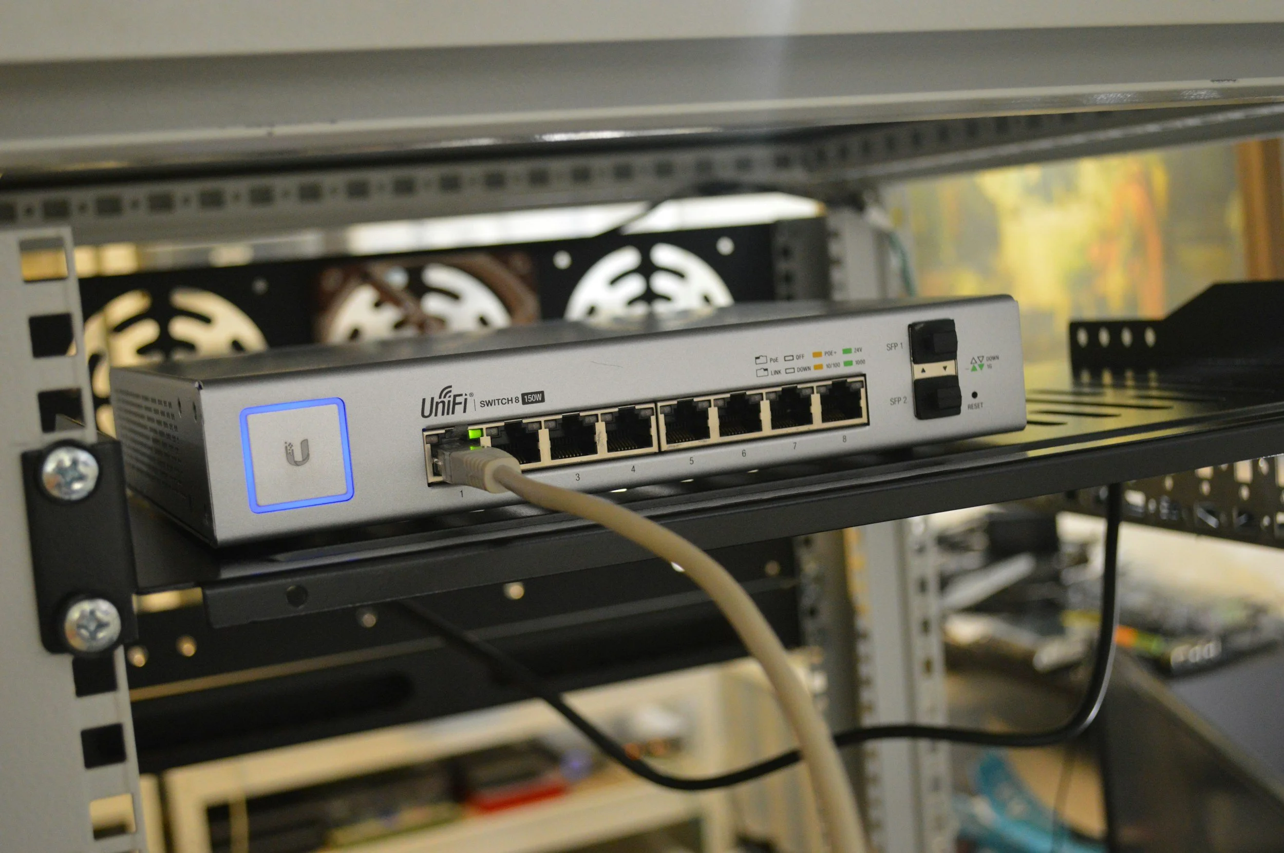 Network switch in server rack with Ethernet cables connected.