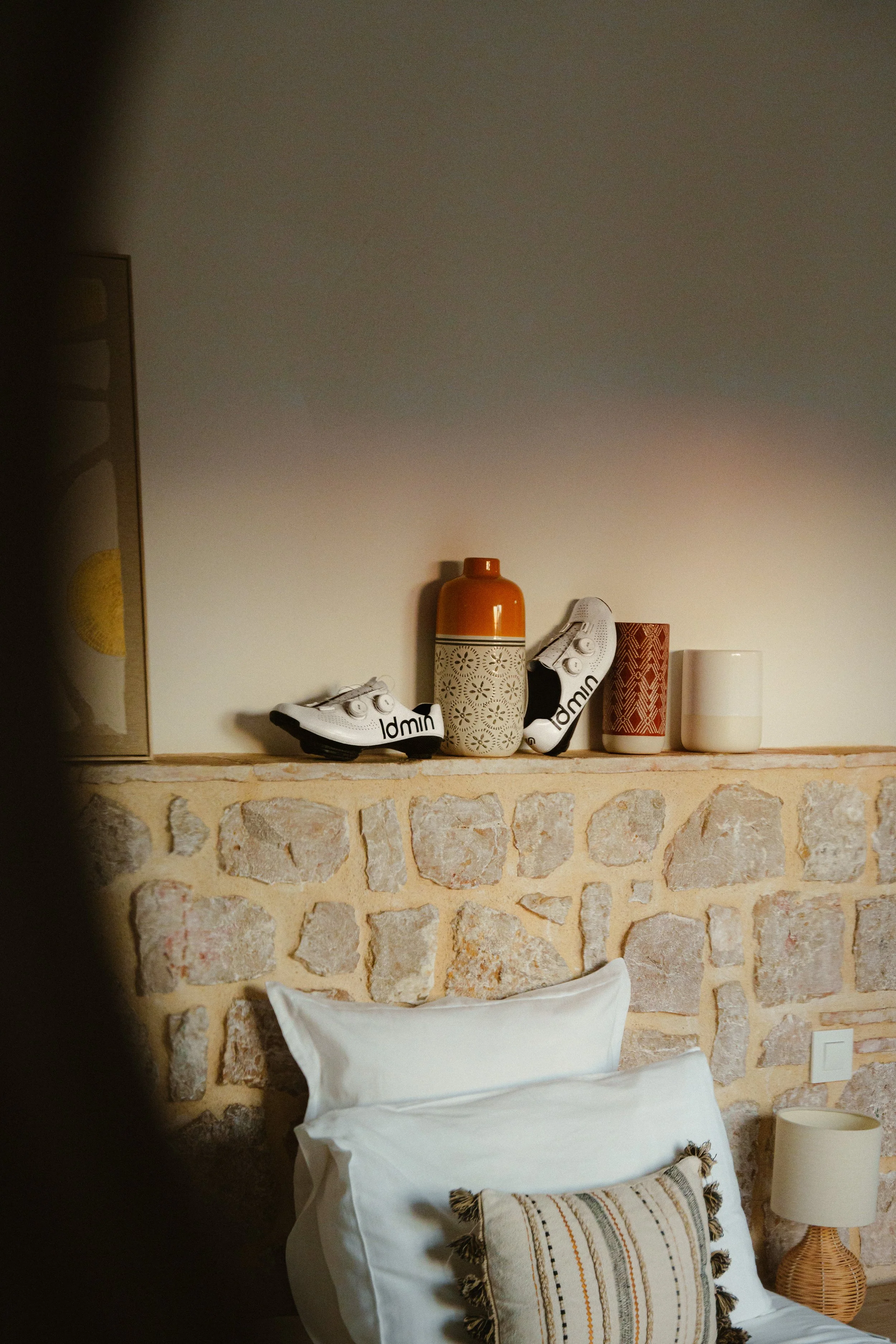 Bedroom with stone wall, pillow, vases, and cycling shoes