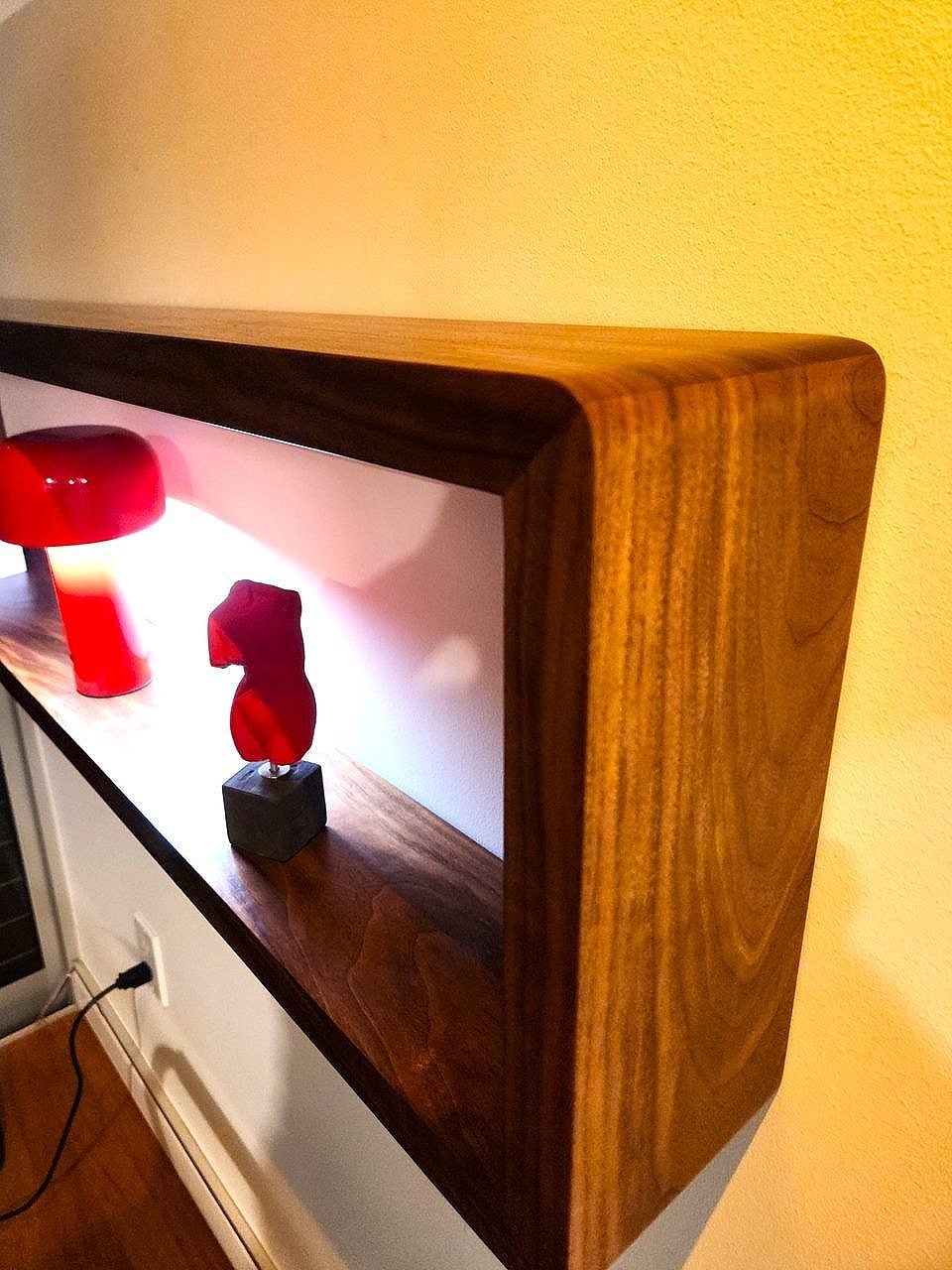 A thick solid walnut floating wall shelf with rounded corners. 