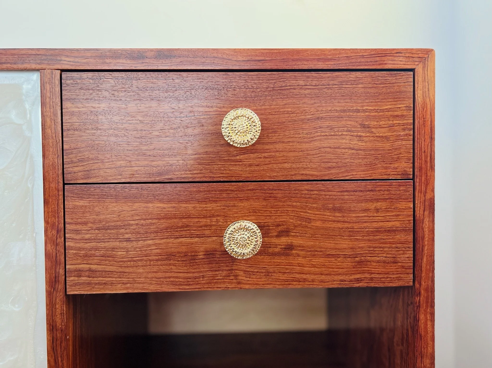 Drawer detail. This credenza has a solid Bubinga exterior with solid hard maple interior shelves and drawers. The doors have a white poured epoxy finish, which strives to both contrast and complement. The white of the epoxy contrasts the reds in the 