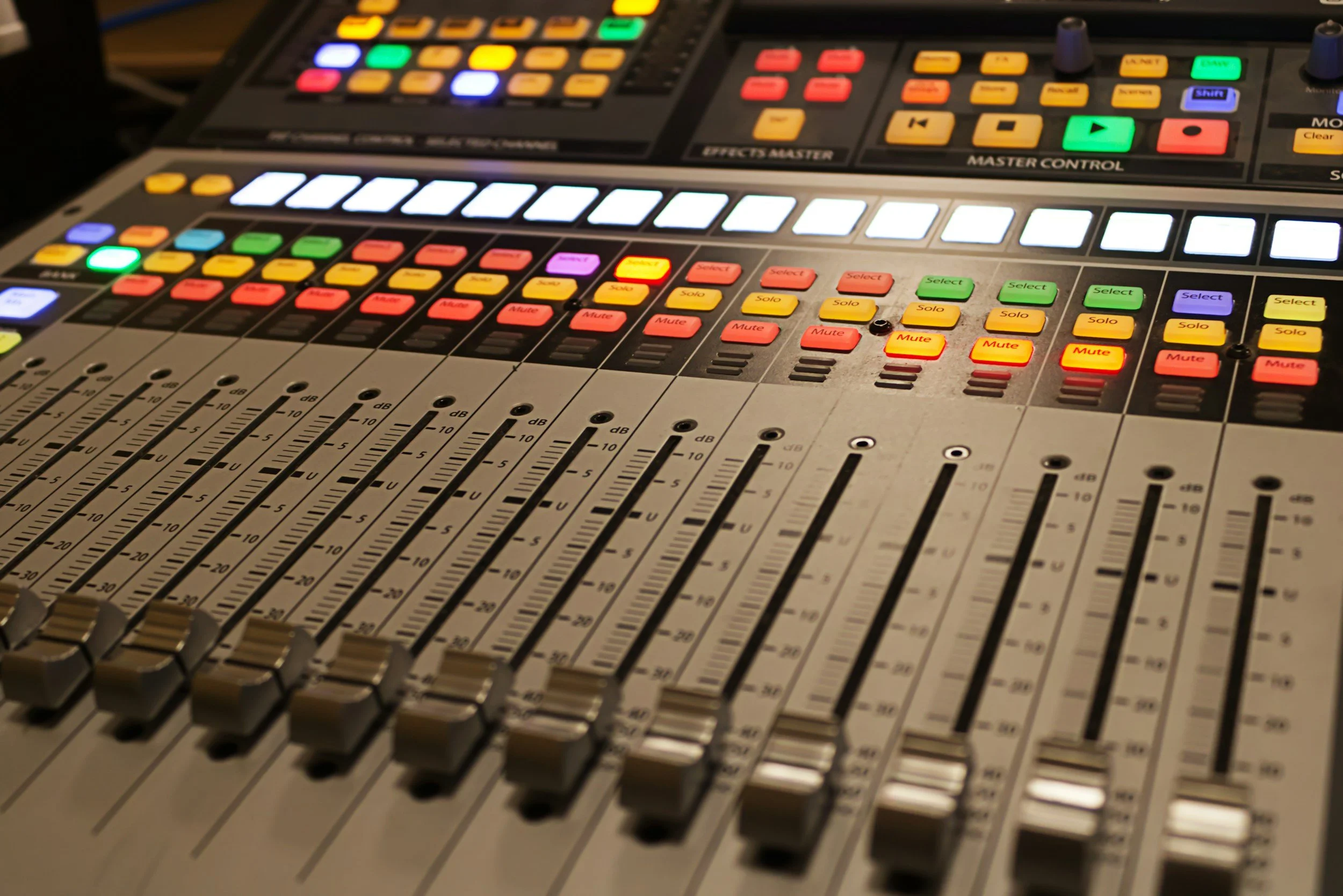 A professional audio mixing console with numerous colorful buttons, sliders, and knobs, used for sound engineering.