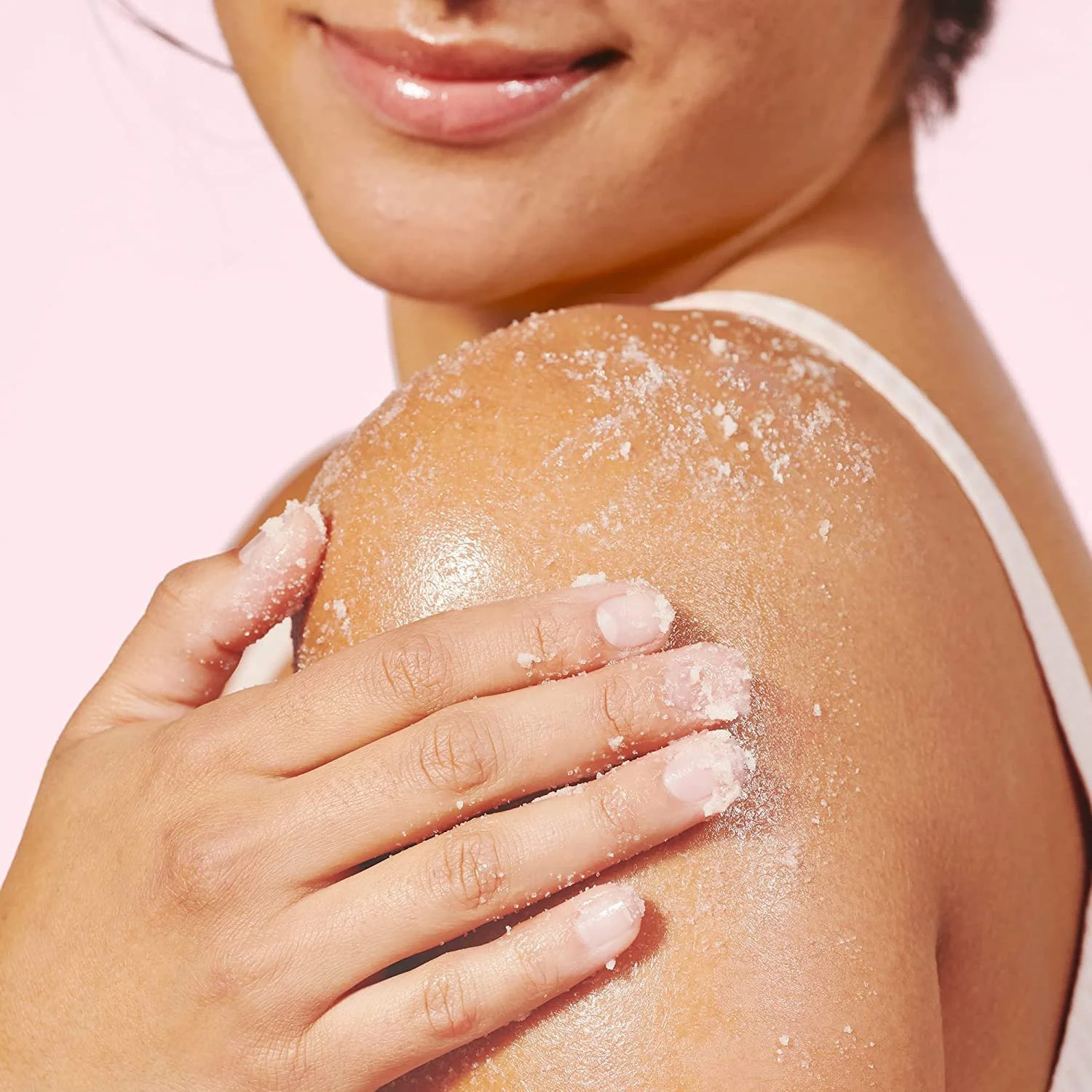 Woman using the Herbivore Coco Rose Body Scrub on her shoulder for smooth, glowing skin.