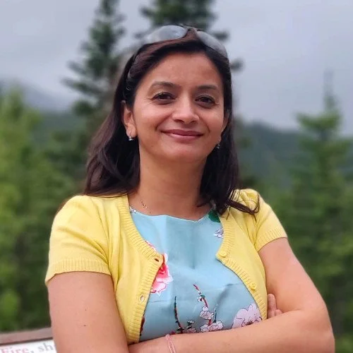 Woman in yellow cardigan outdoors with trees in background
