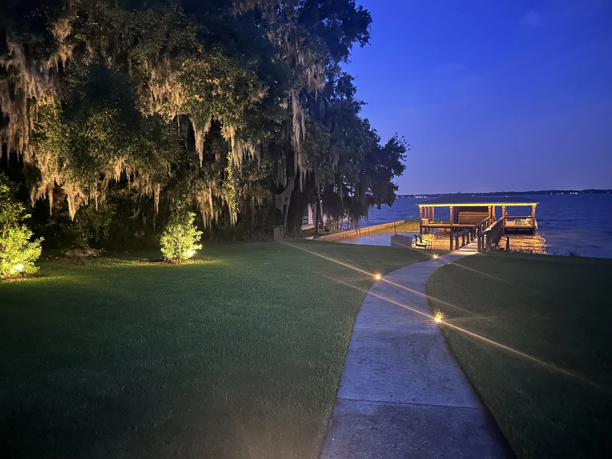 a Windermere dock at dusk, with landscape lighting, and in ground pathway lights