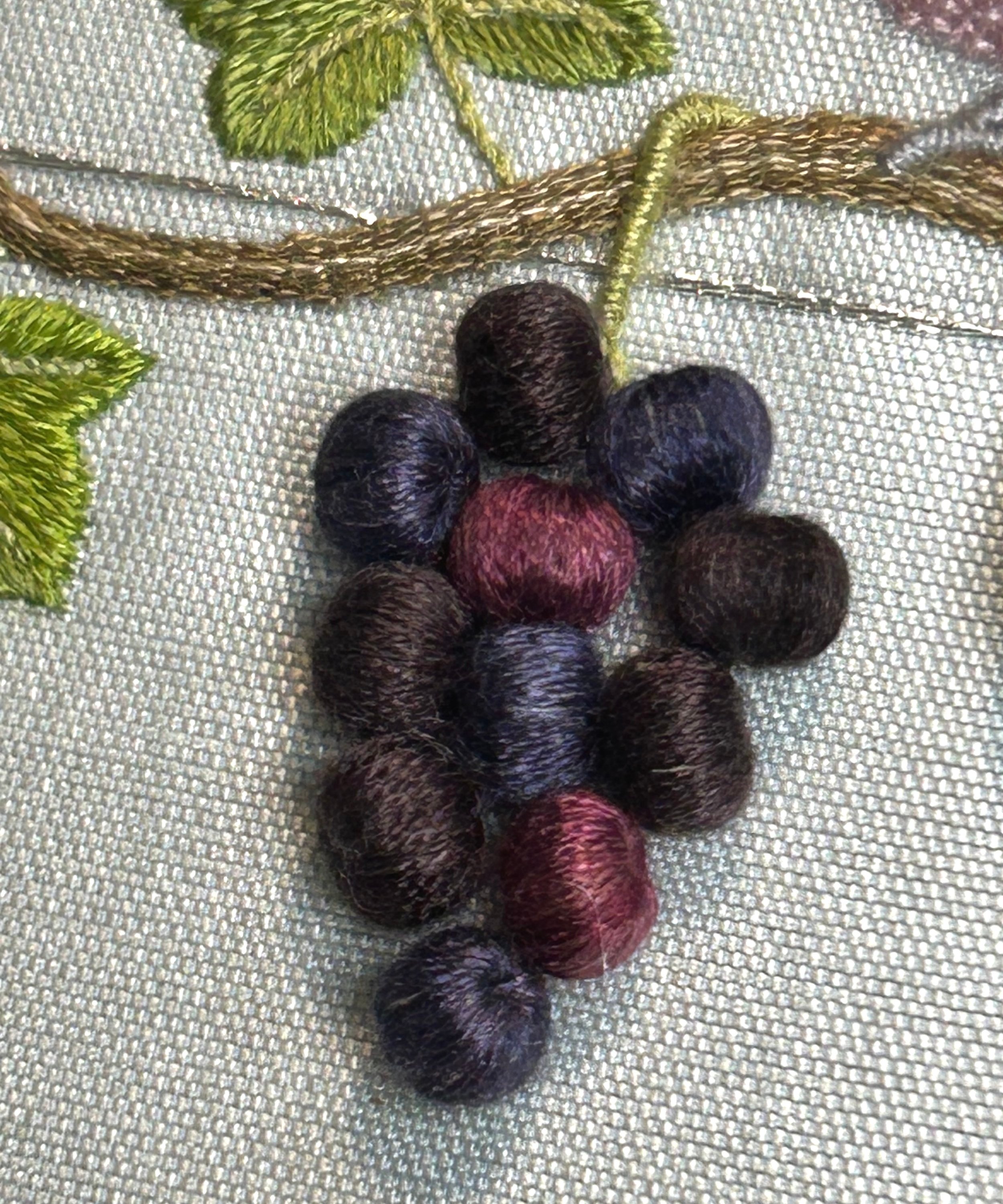 Embroidered grapes created with silk thread over wooden beads.