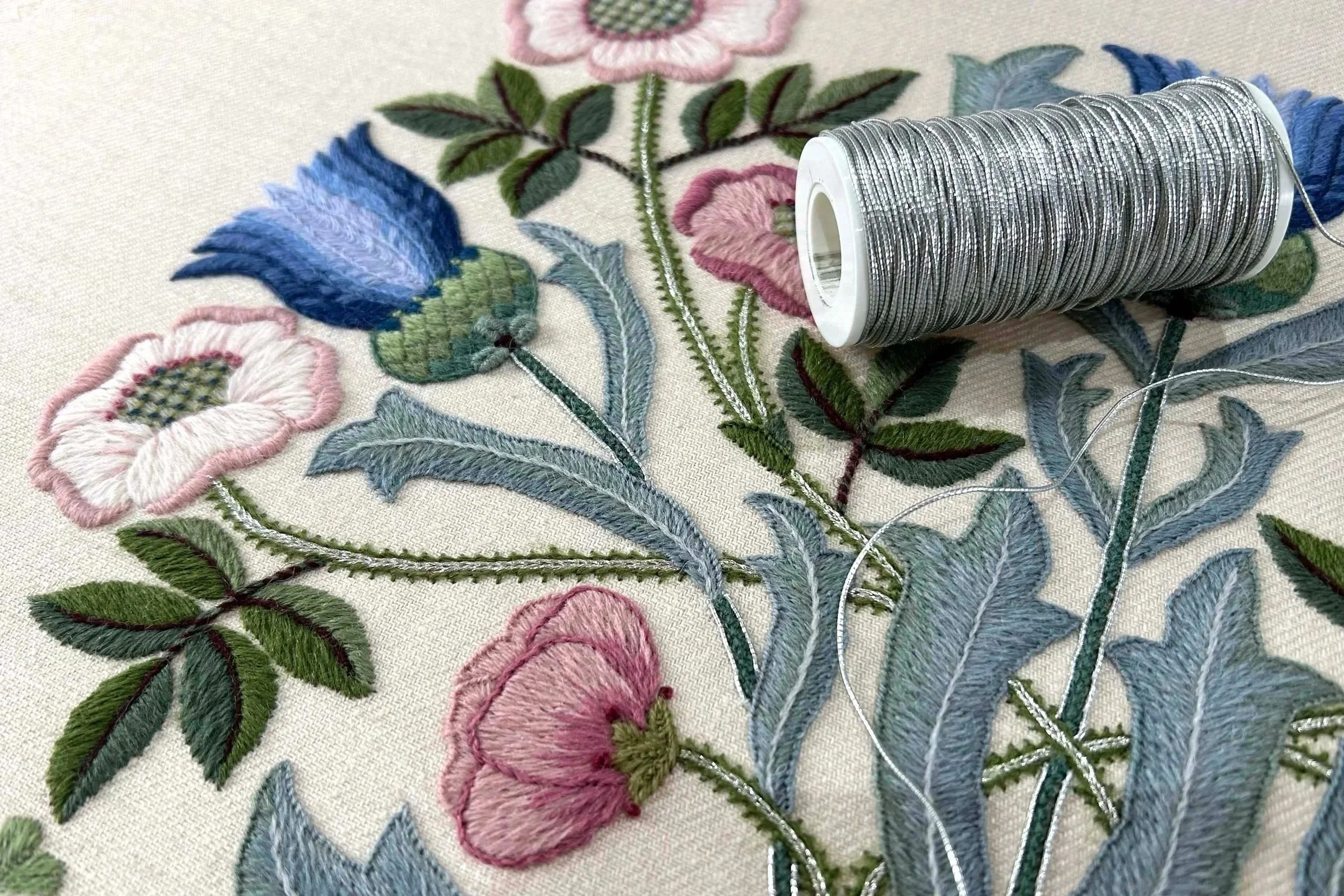 Crewel embroidery, blue thistles and pink roses with silver metallic detail.