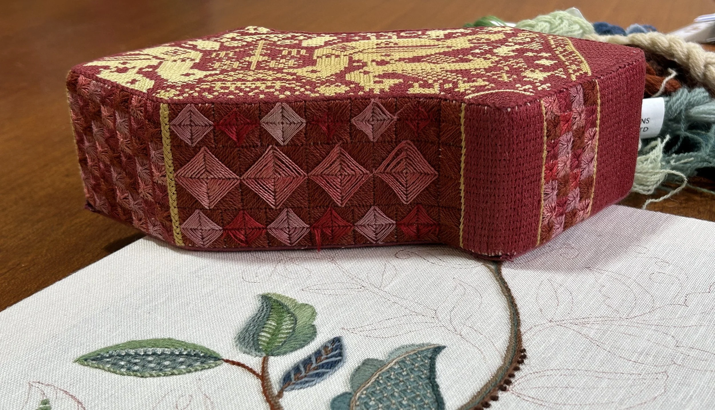 Brick covered with embroidery by Anna Scott. Embroidery worked in a variety of needlepoint stitches using shades of rusty red thread.