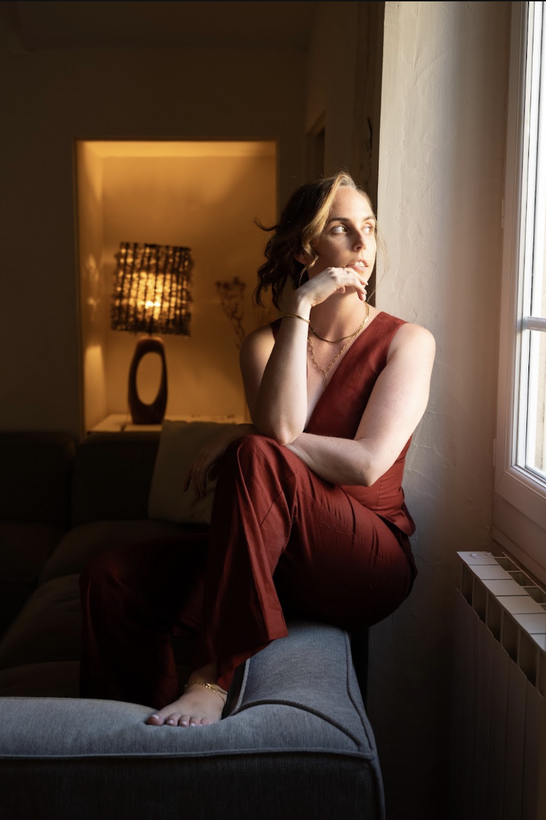 Thought leadership strategist Emily M. Walker sitting on a sofa by a window in a warm, cozy interior.
