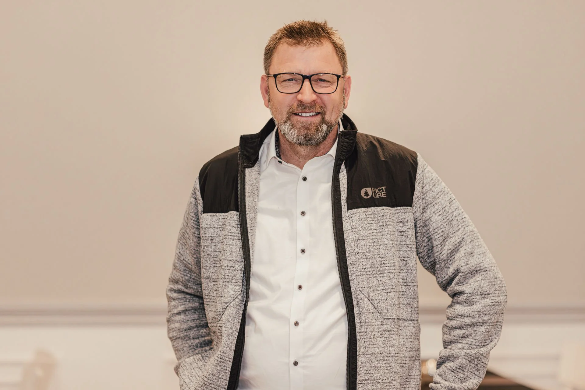 Ein Mann steht in einem weißen Hemd vor einer landwirtschaftlichen Landschaft mit Feldern und Wasserkanälen.
