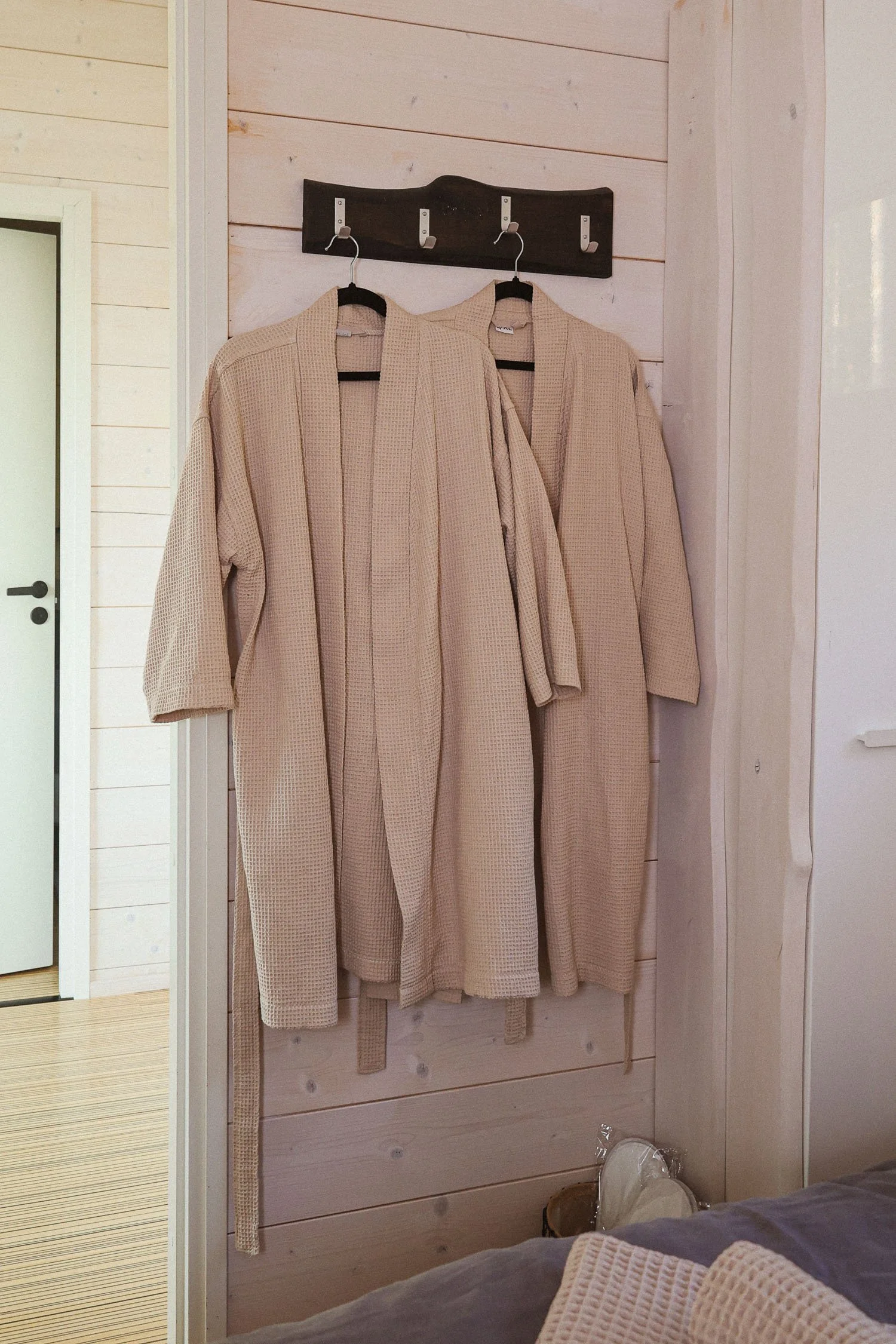 Kaksi kylpytakkia roikkumassa seinällä naulakossa. Villa Kaisla Saimaa keittiö, vuokramökki lähellä Lappeenrantaa, Vehkataipaleella.