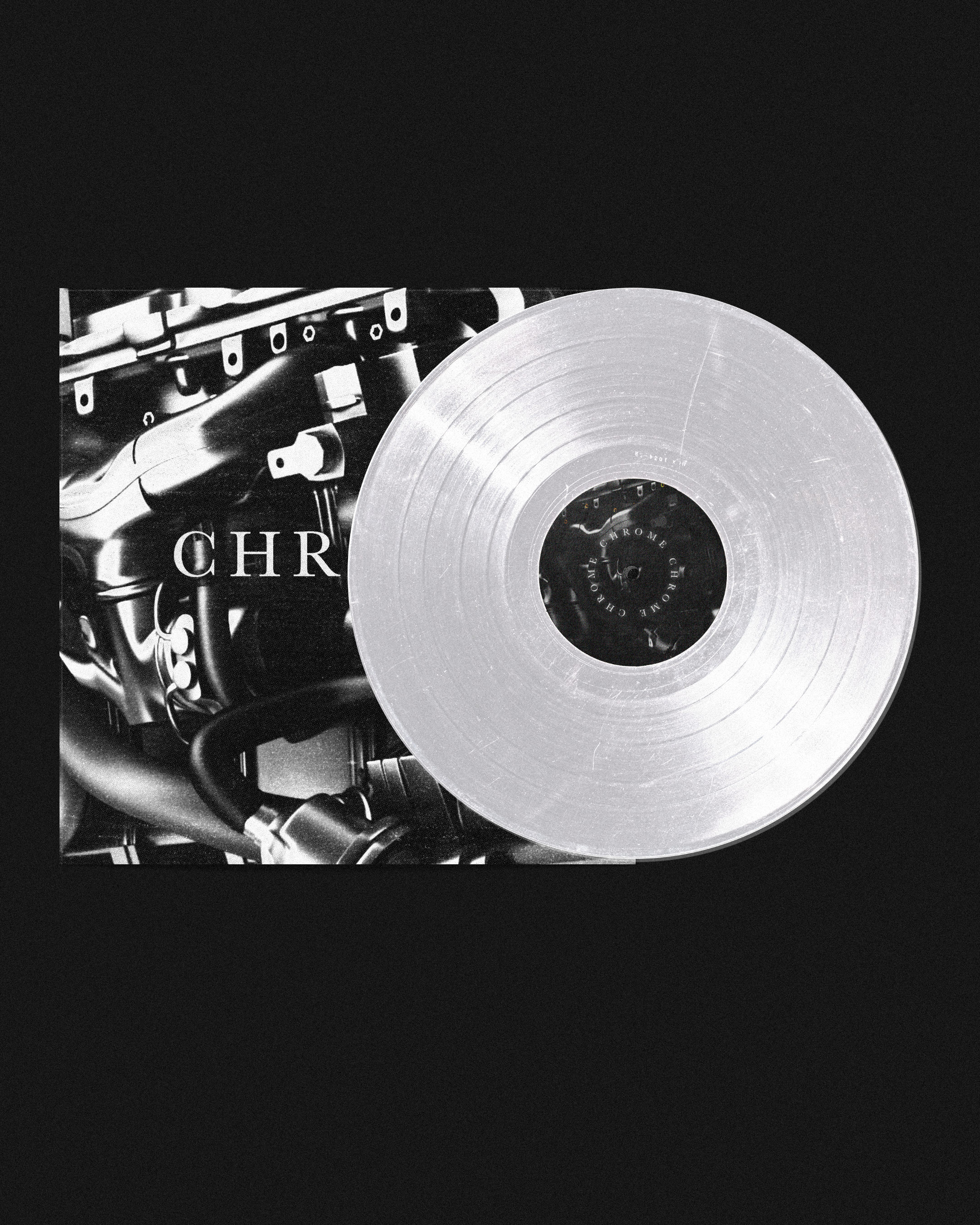 A divided album cover featuring a black and white close-up of a car engine on the left and a translucent vinyl record on the right, with a black background.