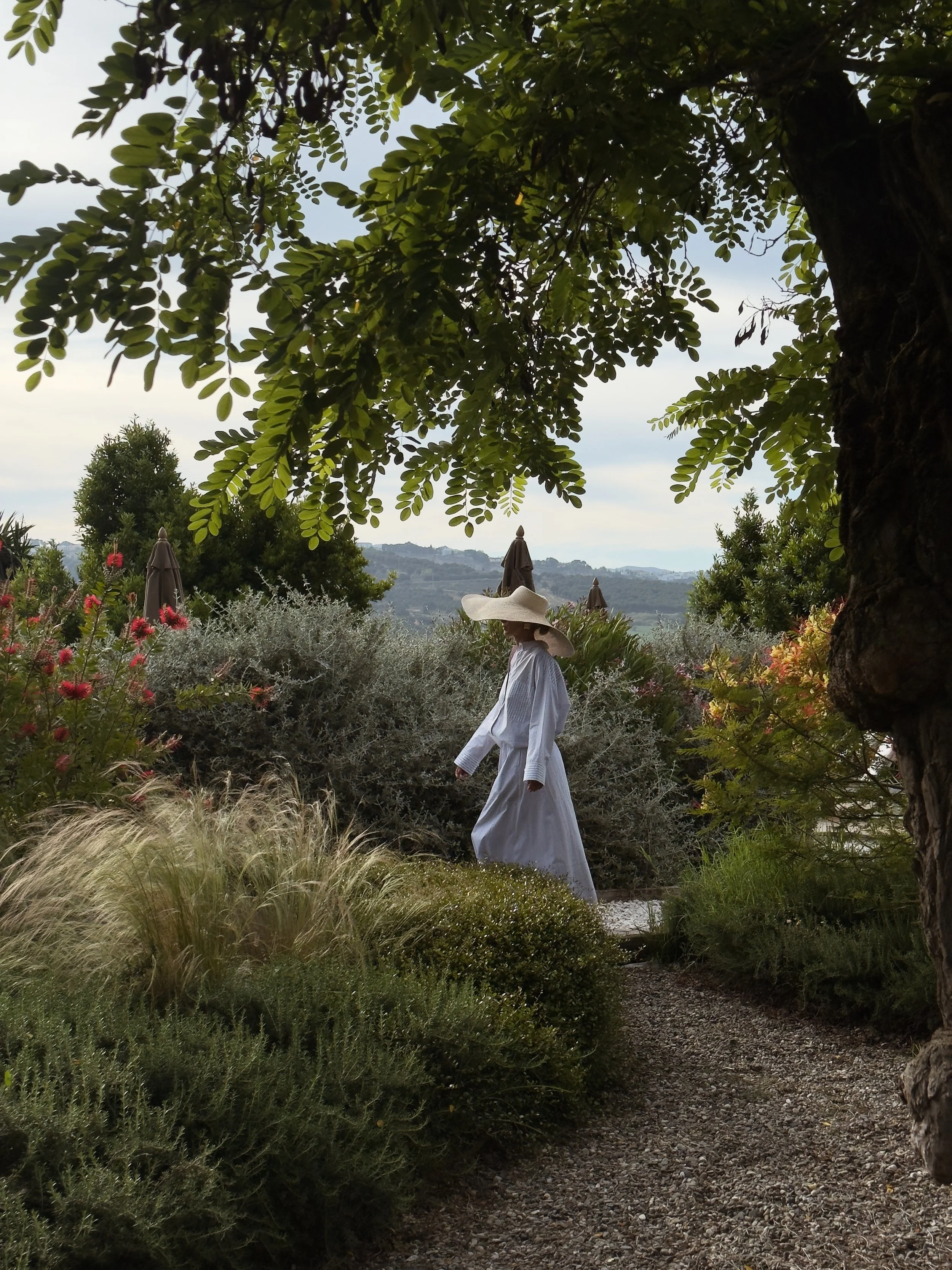 Guest walking through the Mediterranean gardens at Finca La Marquesa, a luxury countryside retreat surrounded by olive groves near Ronda, Andalusia, Spain.