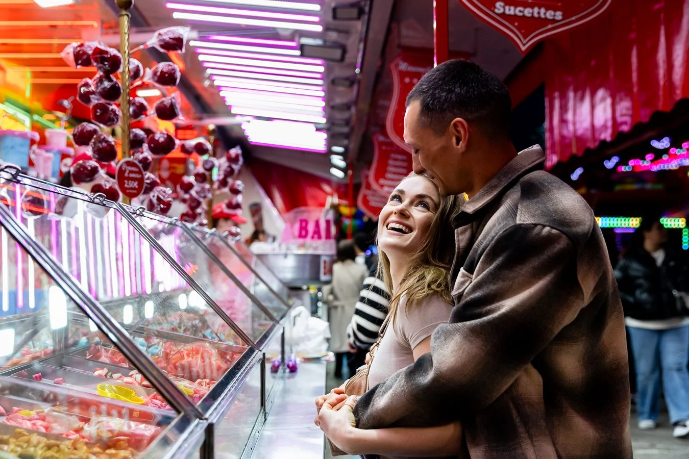 couple complice devant un stand de confiserie et pomme d'amour à la foire des rameaux à Grenoble, photographe mariage Grenoble