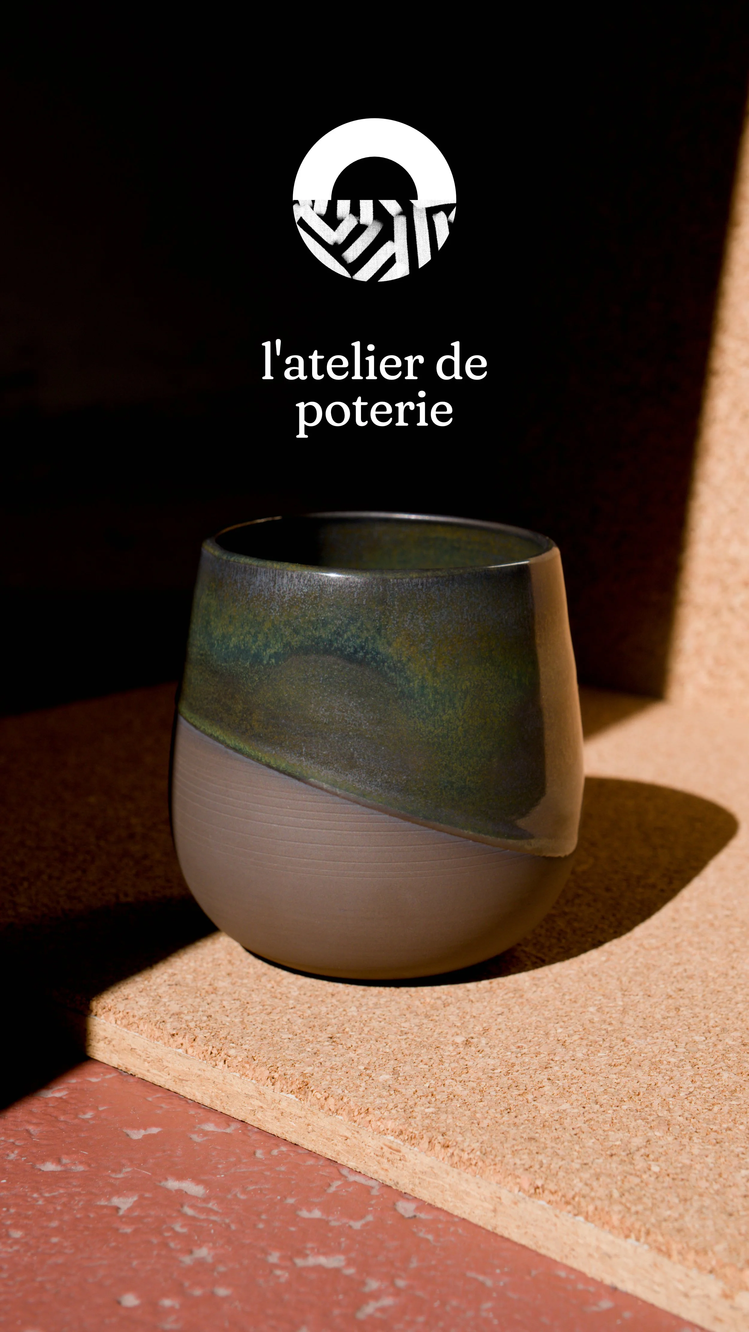 Une pièce en céramique avec une partie supérieure verte et une partie inférieure blanche, posée sur une surface en pierre ou en béton. Le fond est sombre avec un éclairage qui met en valeur la poterie.