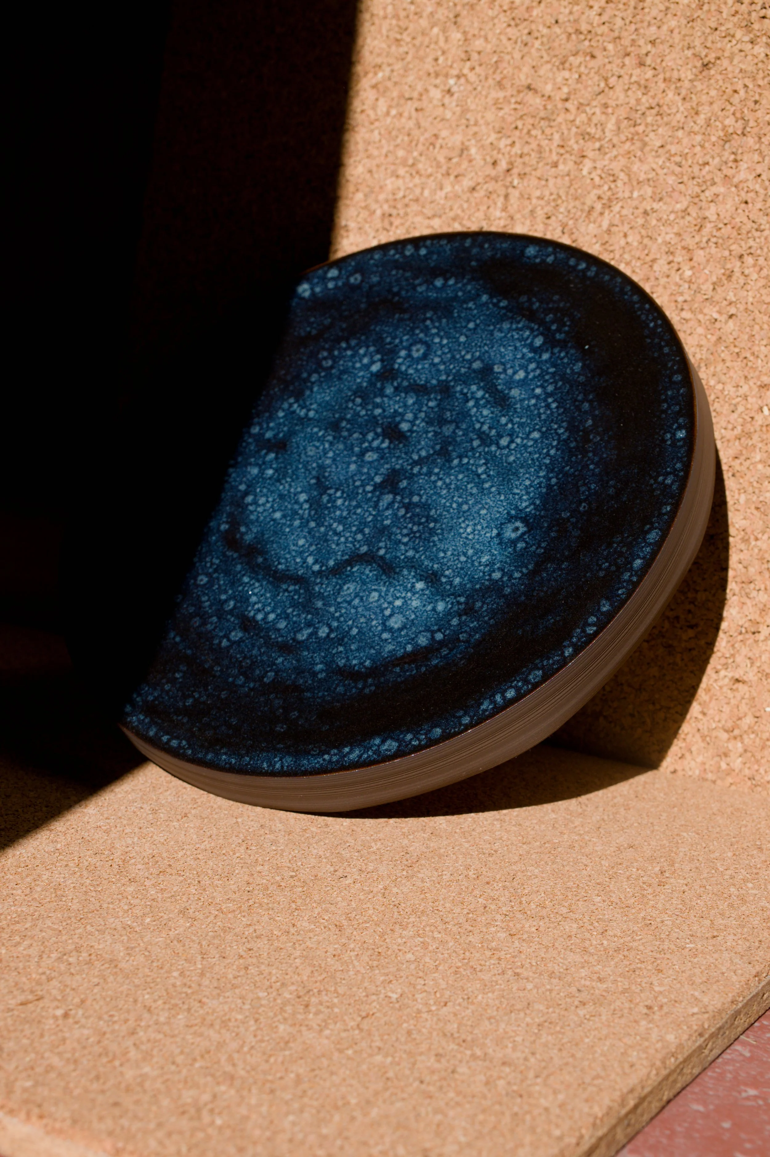 Un plat à tarte bleue avec des motifs, posée sur une surface en liège.