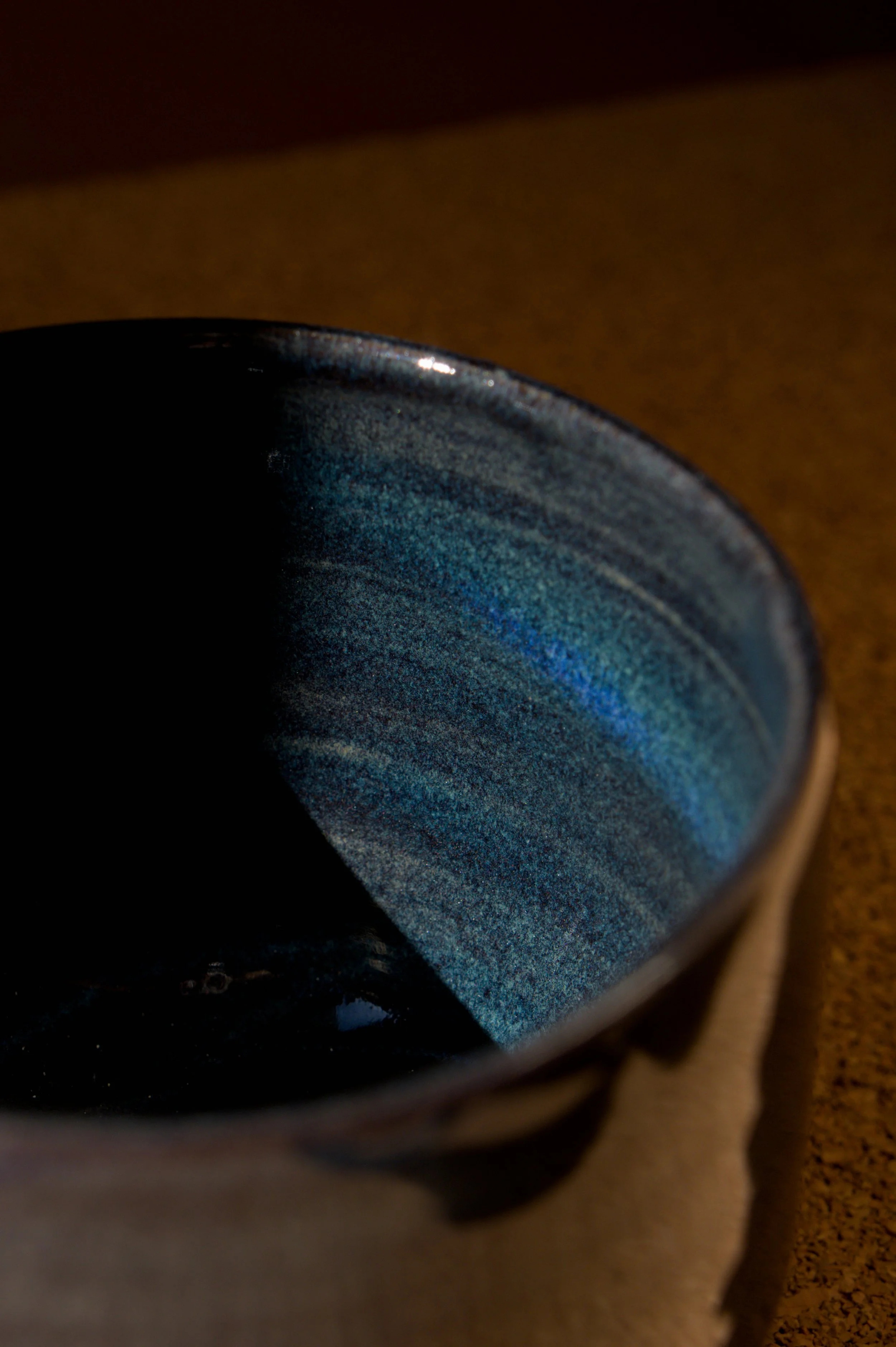 Gros plan d'une tasse en céramique bleue dans un environnement sombre.